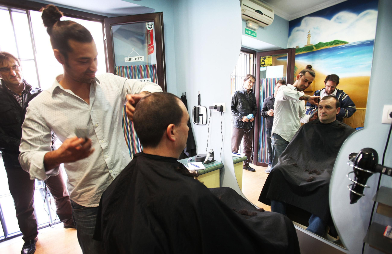 Un peluquero atiende a un cliente en su establecimiento.