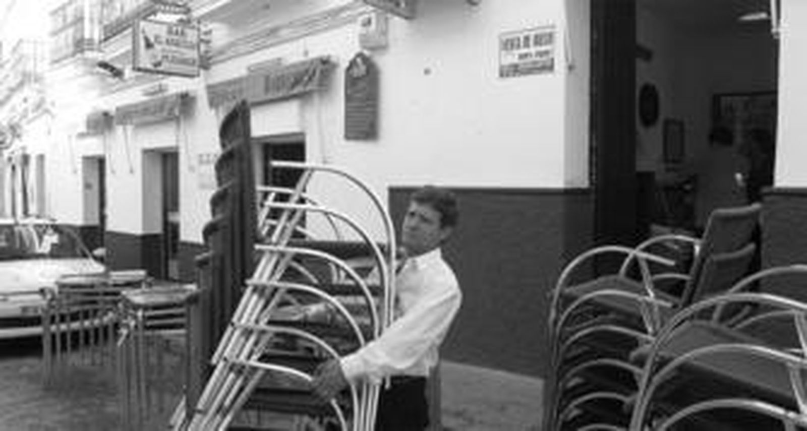 Un camarero coloca las sillas frente al bar El Arquillo, que solía frecuentar la víctima.