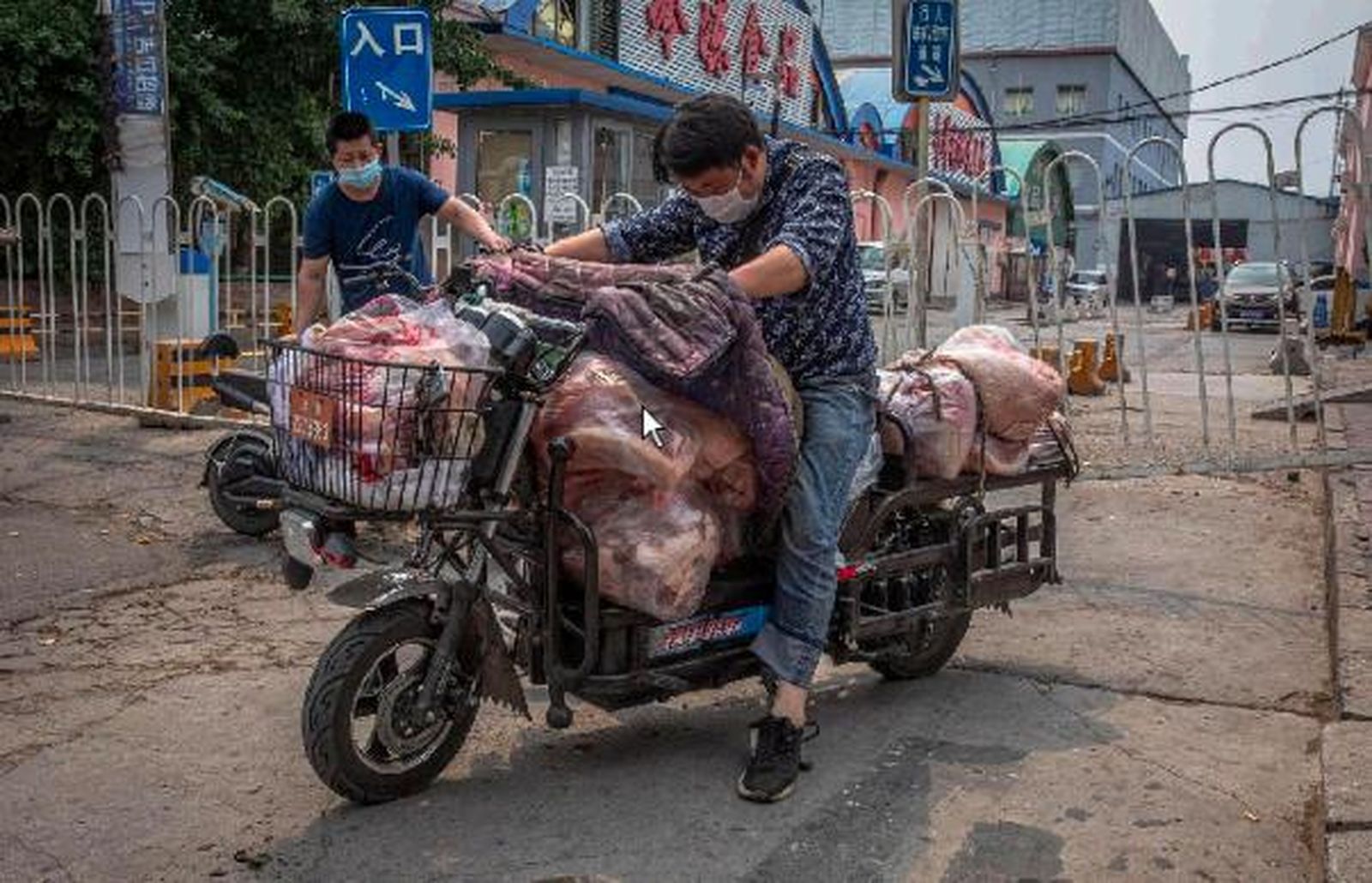 Un hombre en moto a las afueras del mercado foco del nuevo brote de coronavirus en Pekín.