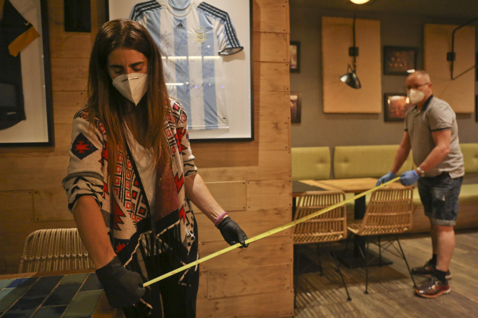 Trabajadores de un bar en Málaga miden la distancia entre las mesas.