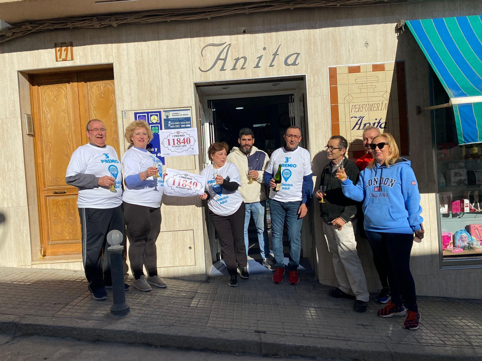 Varias personas celebran en la droguería Anita de Castro del Río el tercer premio de la Lotería de Navidad