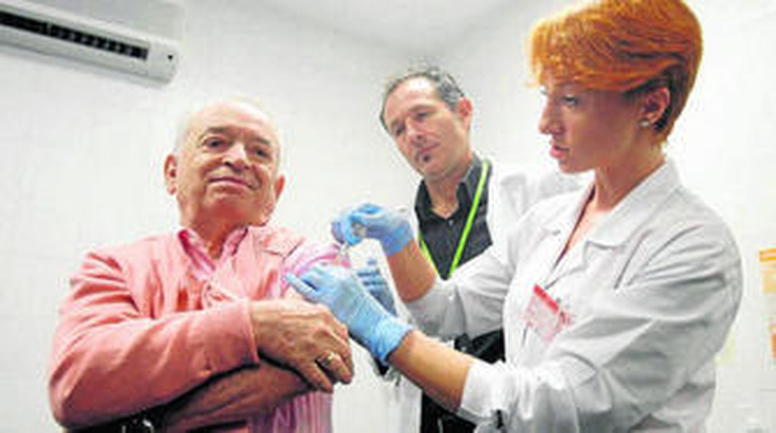 Una enfermera administra la vacuna de la gripe a un paciente.