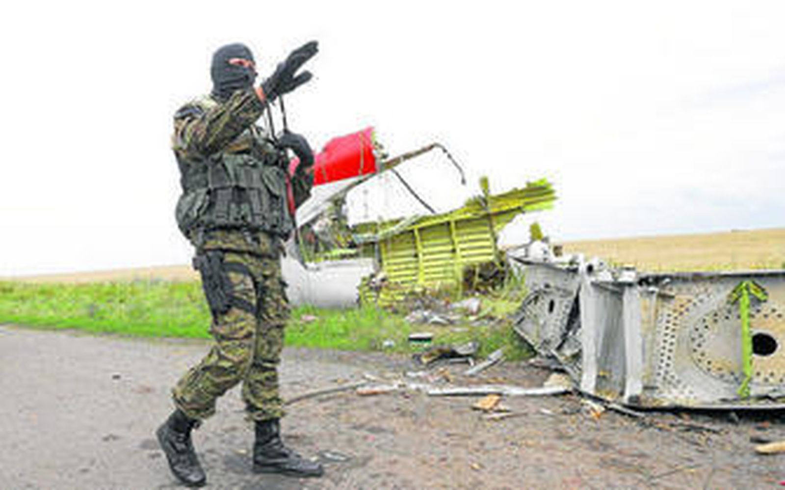Un rebelde armado hace señales a los periodistas para que abandonen el lugar donde cayó el avión en la región de Donetsk.