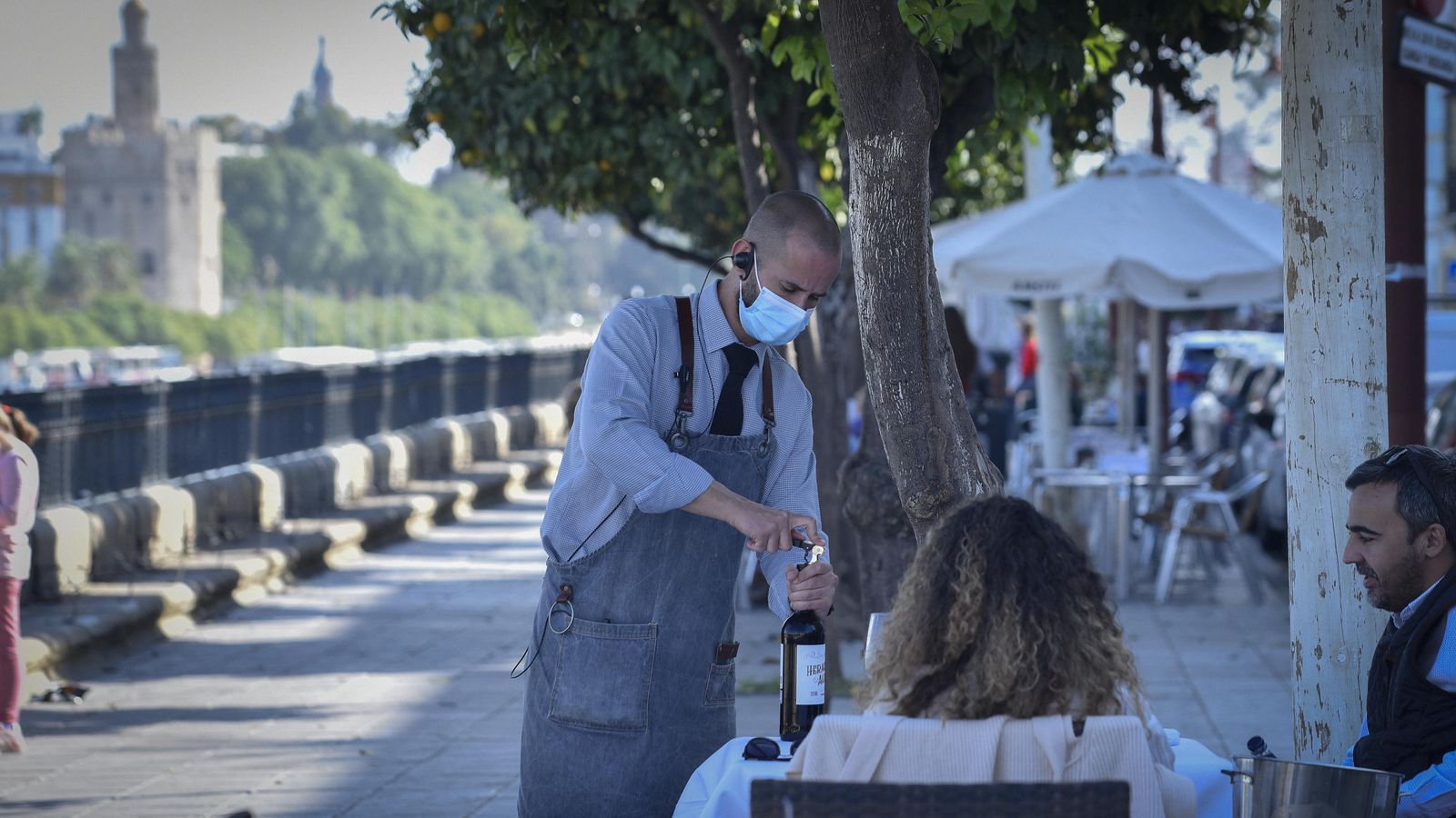 Un camarero sirve a una pareja en la terraza de un bar de la calle Betis.