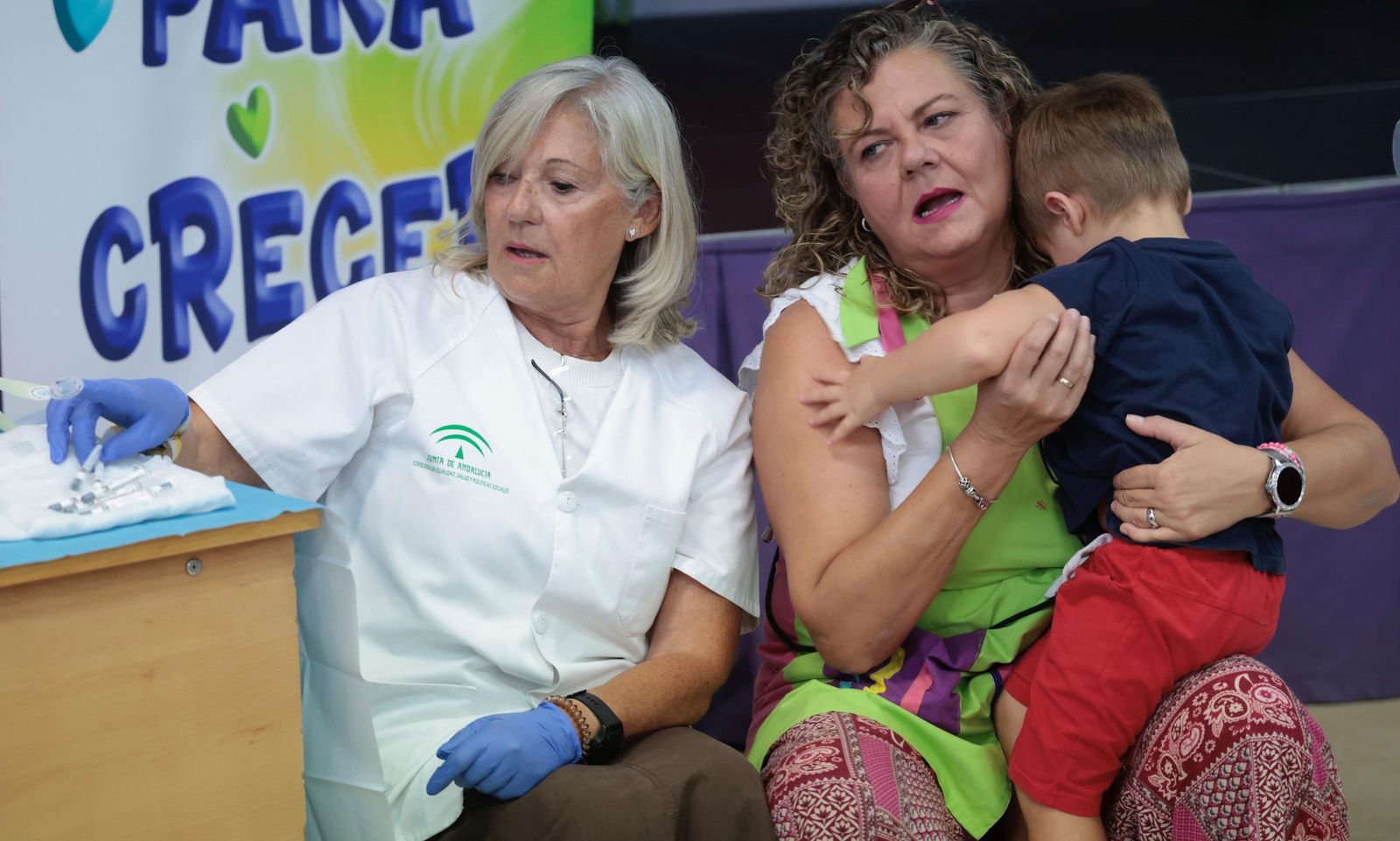 Enfermera y profesora junto a los menores en el inicio de la vacunación contra la gripe en el CEIP Pablo Picasso de Sevilla.