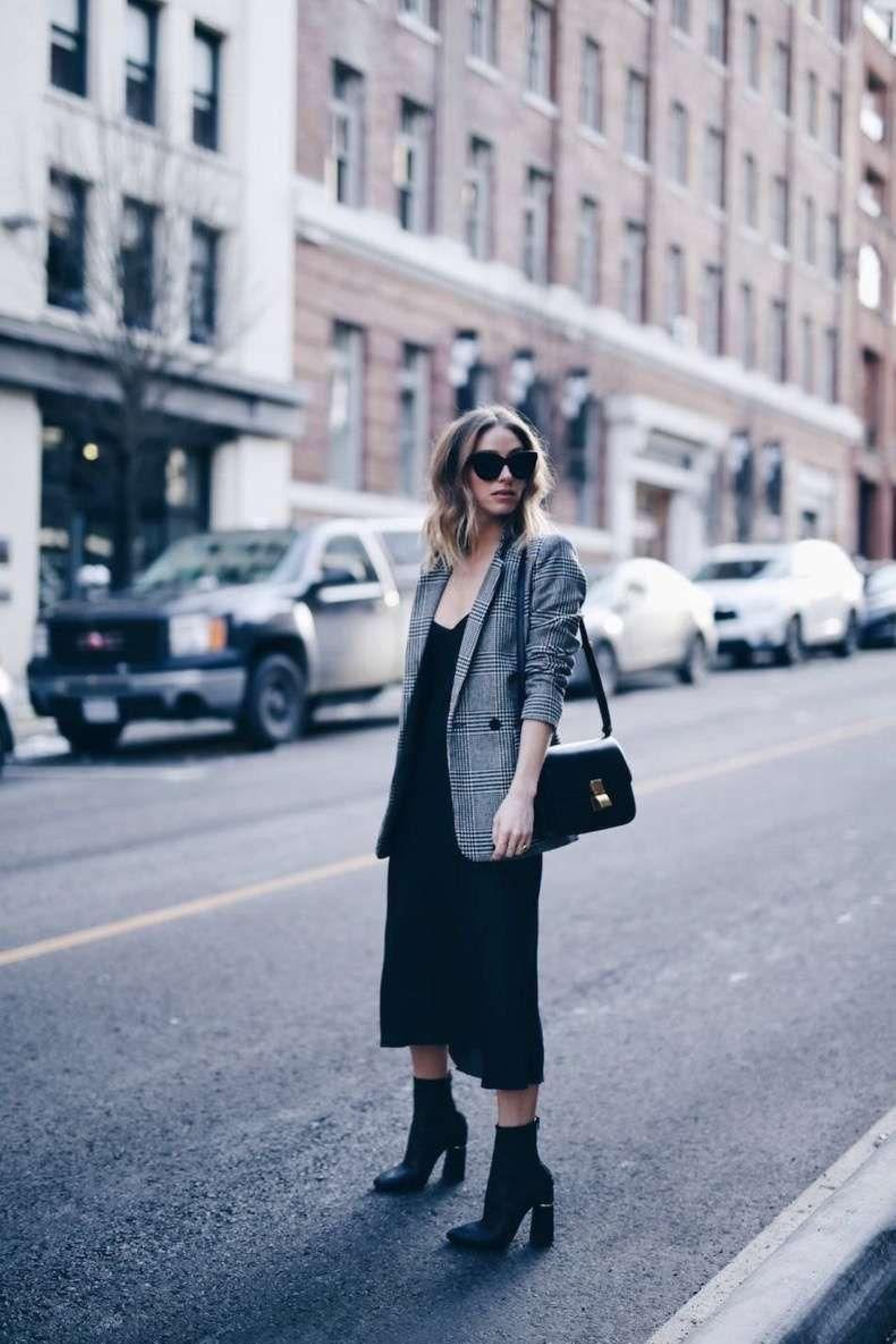 Look con vestido negro y americana de cuadros.