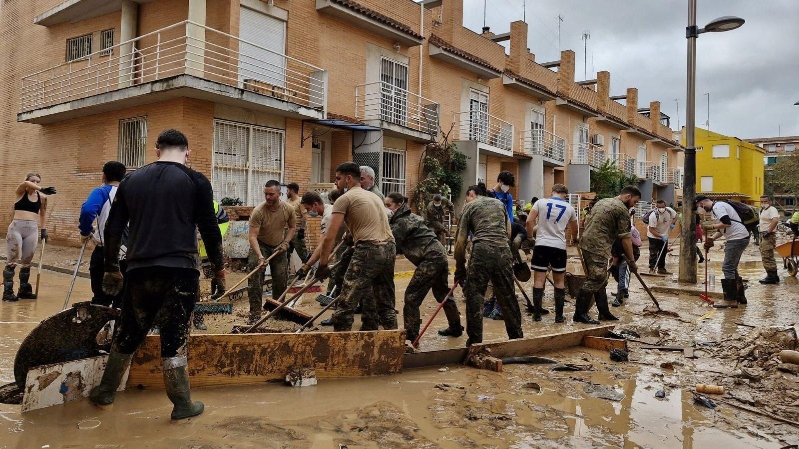 Legionarios y vecinos retiran el barro de una calle arrasada por las riadas