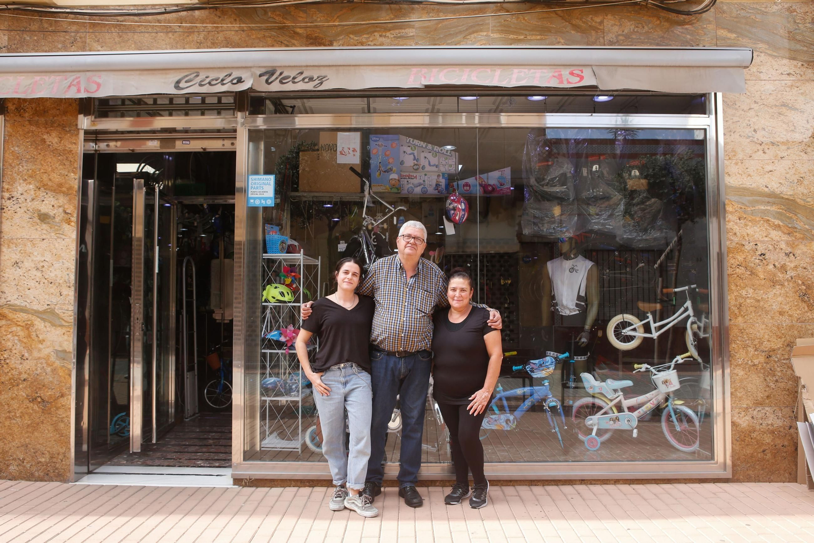 Moisés Fernández, su hija Maite y la limpiadora de la tienda, en las puertas de Ciclo Veloz. Moisés Fernández, su hija Maite y la limpiadora de la tienda, en las puertas de Ciclo Veloz.