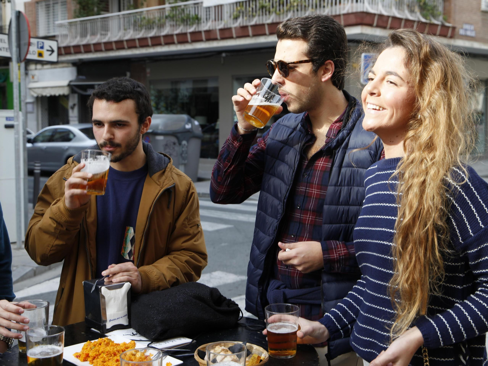 Jóvenes bebiendo cerveza en la puerta de un establecimiento.