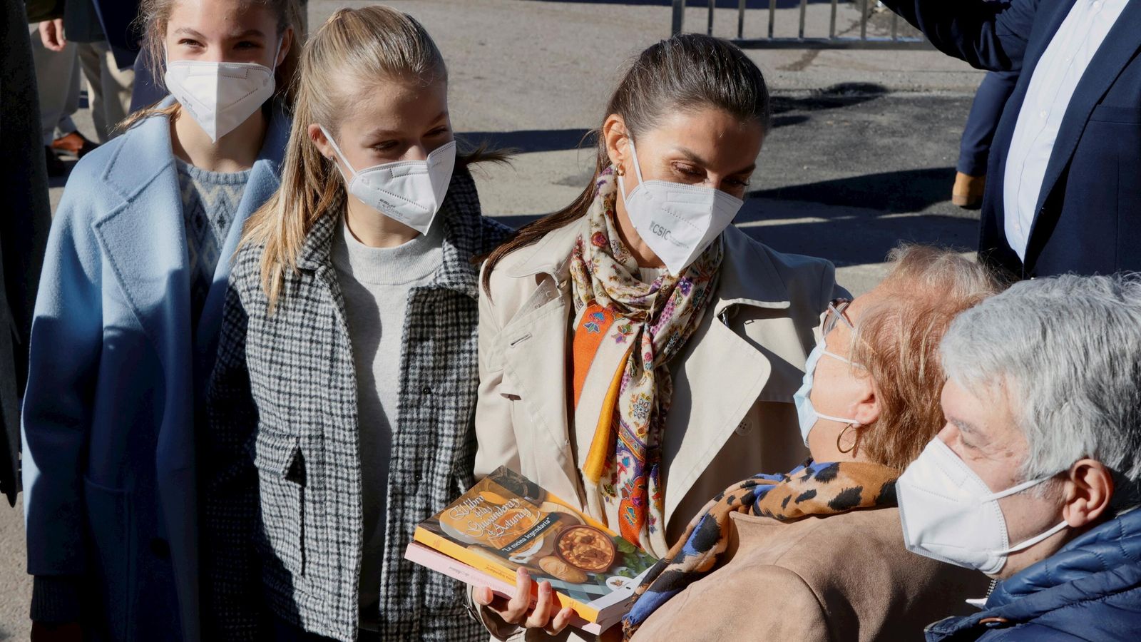 La Reina, agradeciendo a una vecina asturiana su obsequio de un libro, ante la mirada de sus hijas.