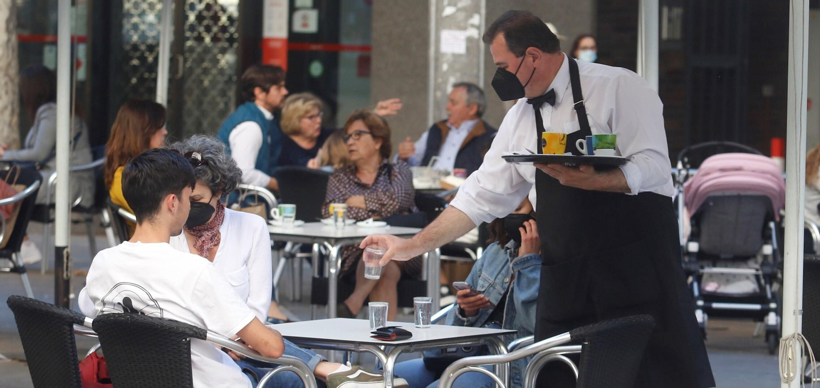 Un camarero atiende una mesa en una terraza.