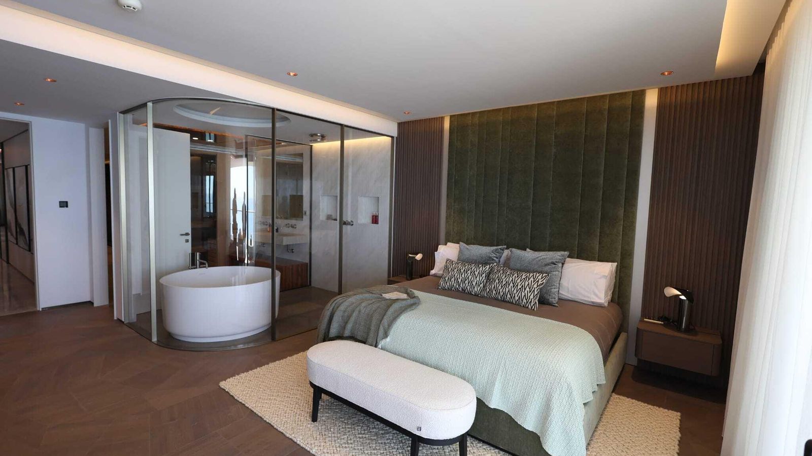 Habitación principal del ático, con una mampara curva hecha a medida en la separación entre baño y dormitorio.