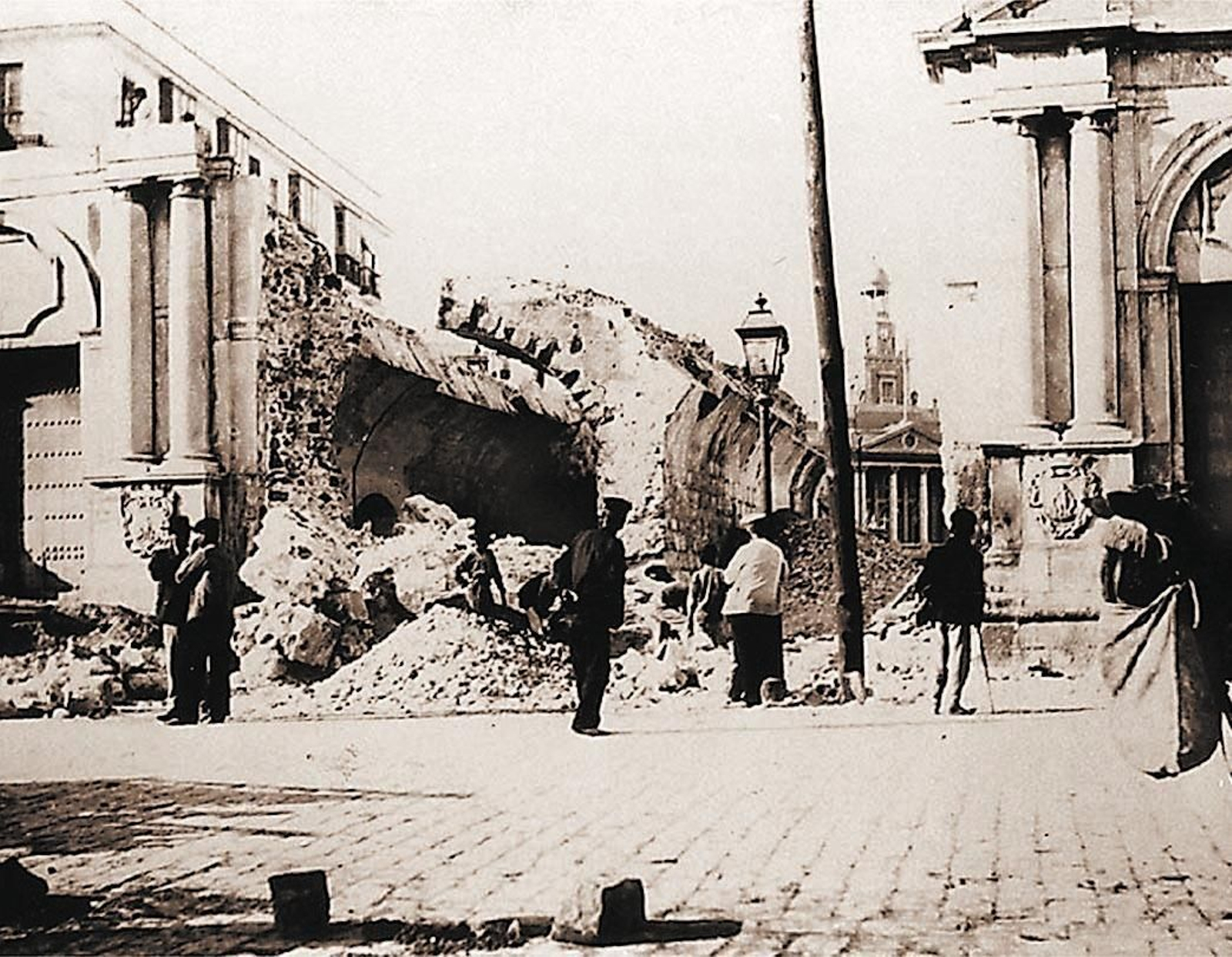 Unos paseantes miran el estado de la muralla tras su demolición.