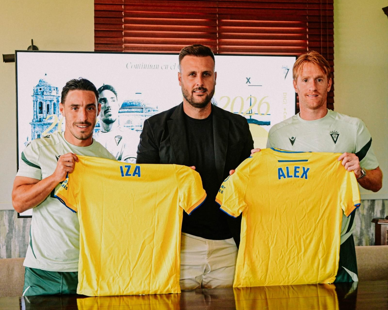 Iza y Álex sostienen su camiseta en compañía de Juan Cala.