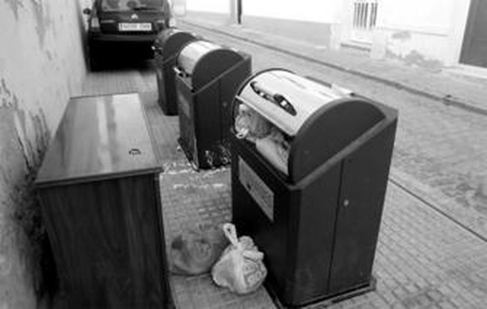 Buzones de los contenedores soterrados, con basura en el exterior, en la calle Lista.