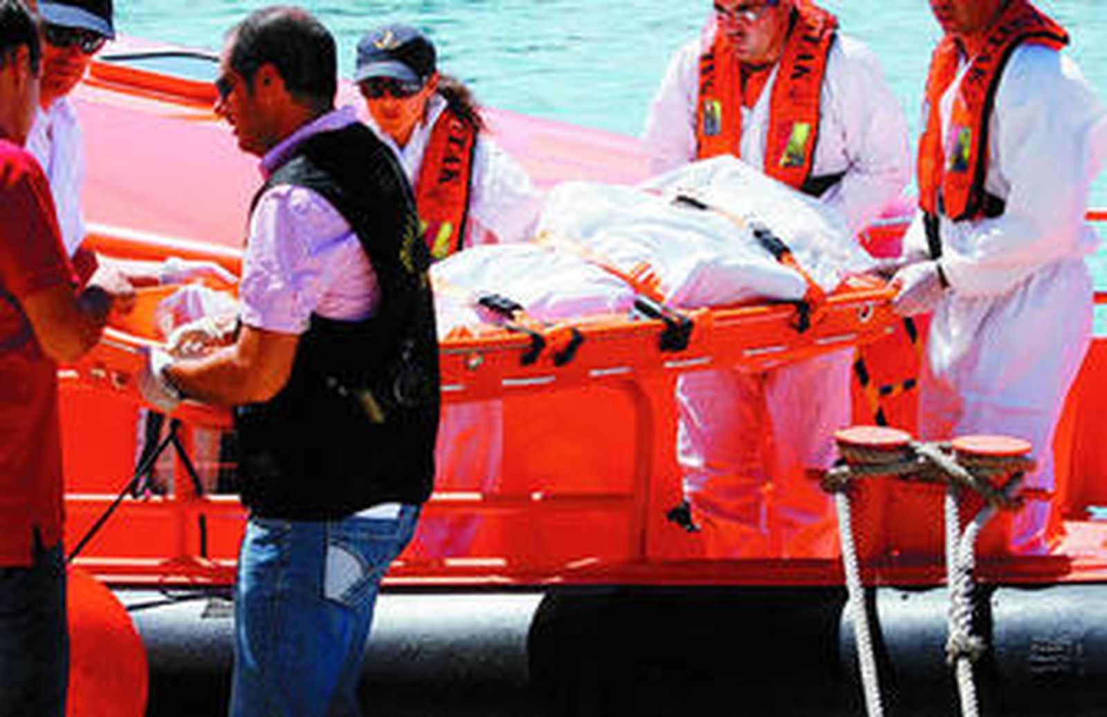 Miembros de Salvamento Marítimo trasladan el cuerpo de la joven muerta.