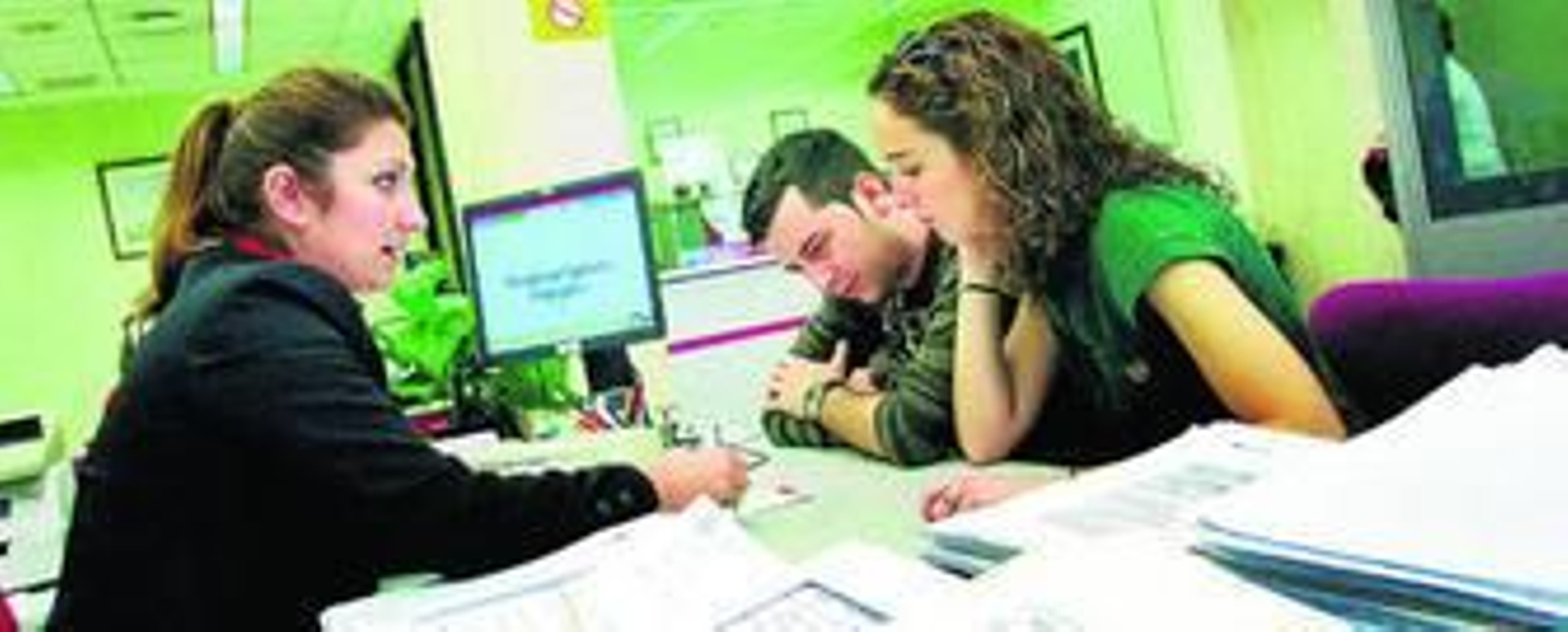 Una empleada de banca en Málaga muestra las condiciones de una hipoteca a dos jóvenes en una imagen de archivo.