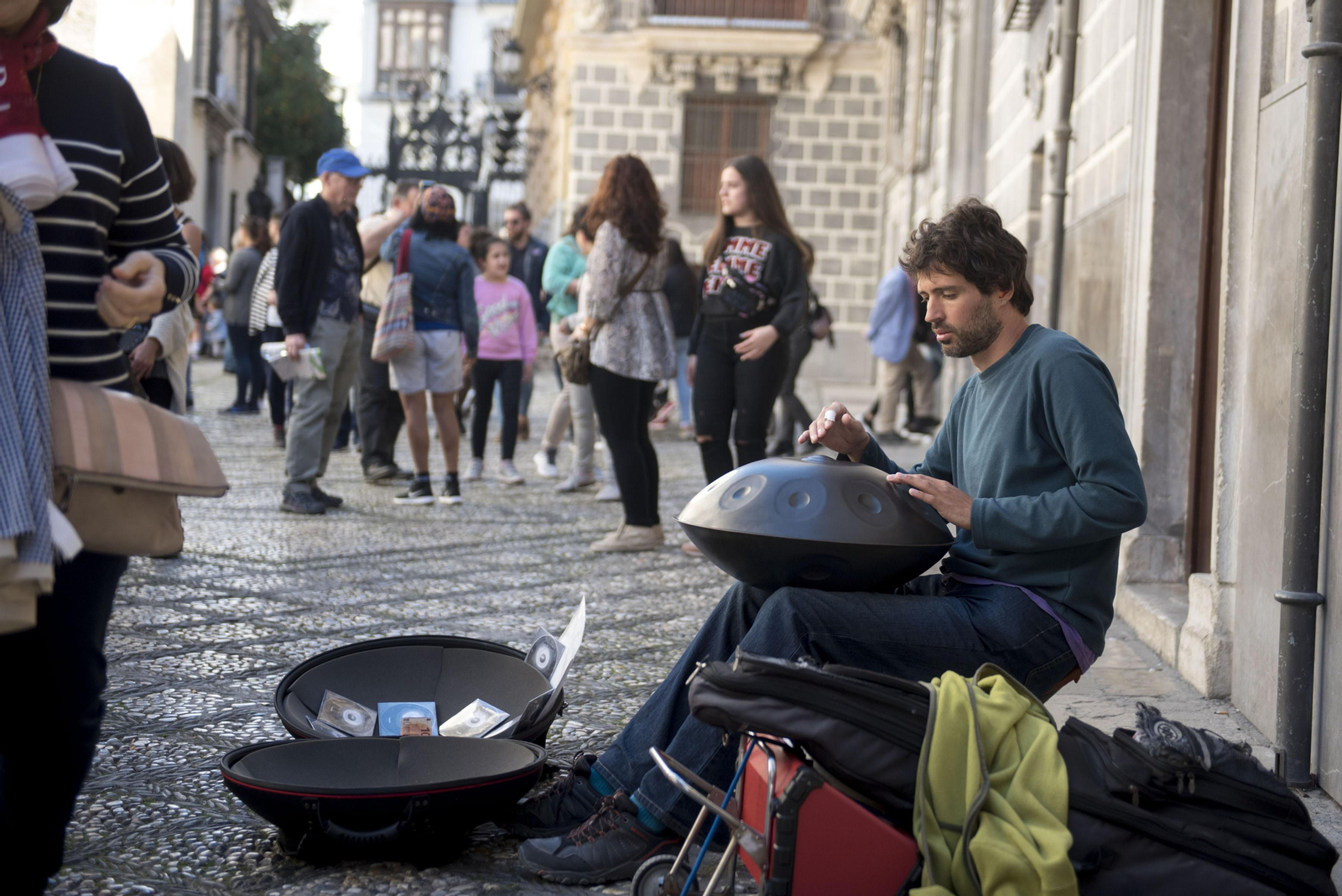 Un artista callejero toca su hang, un instrumento de percusión musical, en la calle Oficios, delante de la fachada del Palacio de La Madraza