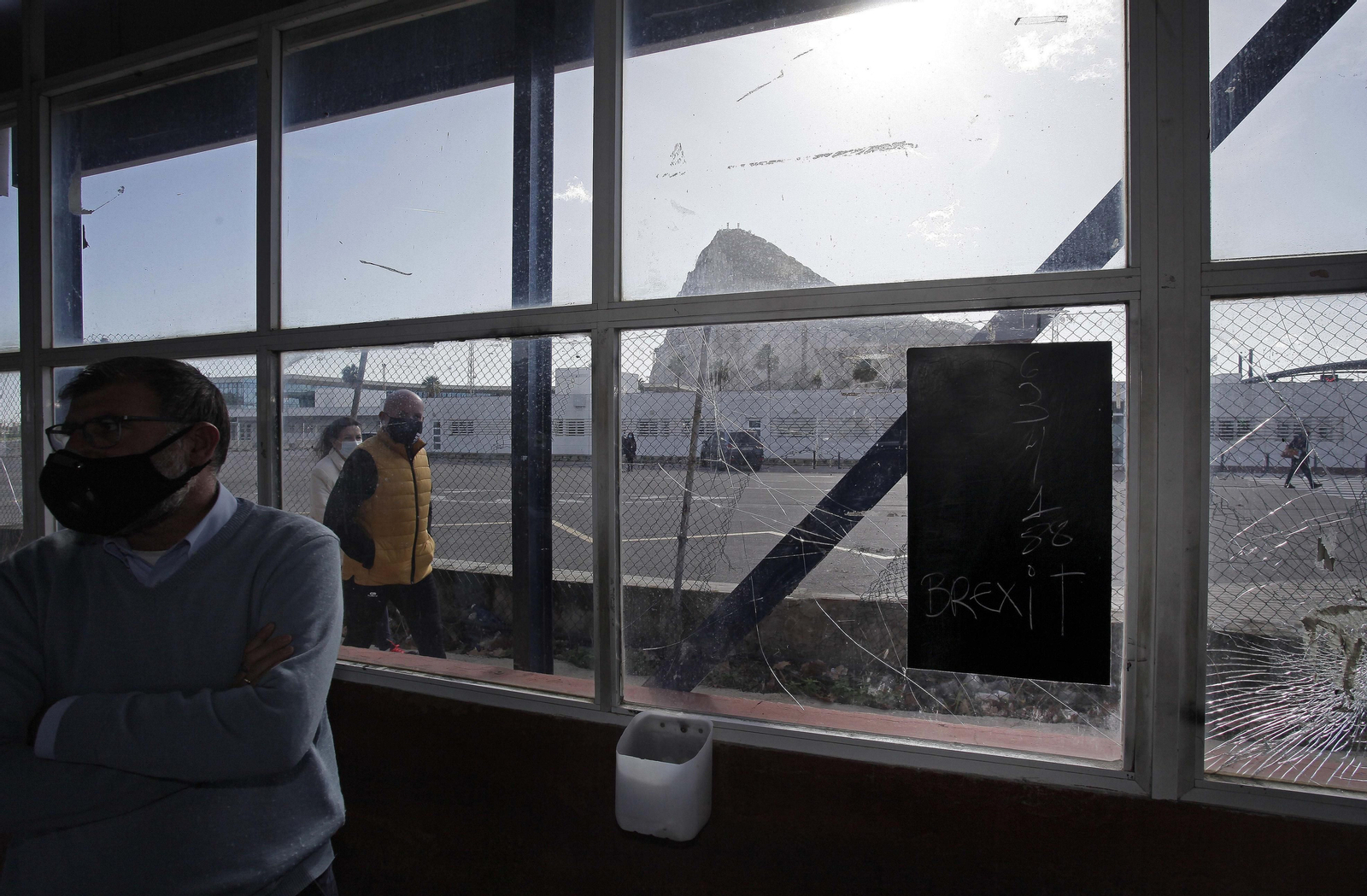 Dos personas caminan con el Peñón al fondo.