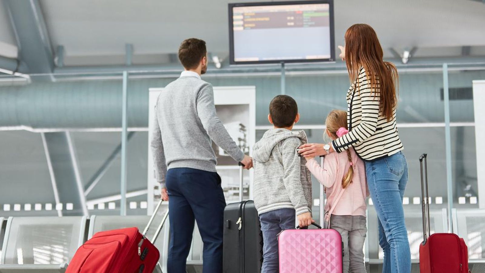 Una familia consulta el panel de salida y combinaciones de vuelos