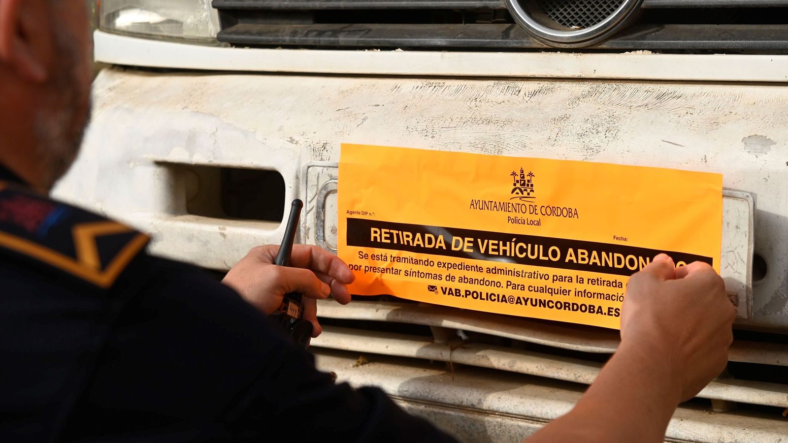 Un policía local pone una pegatina naranja.