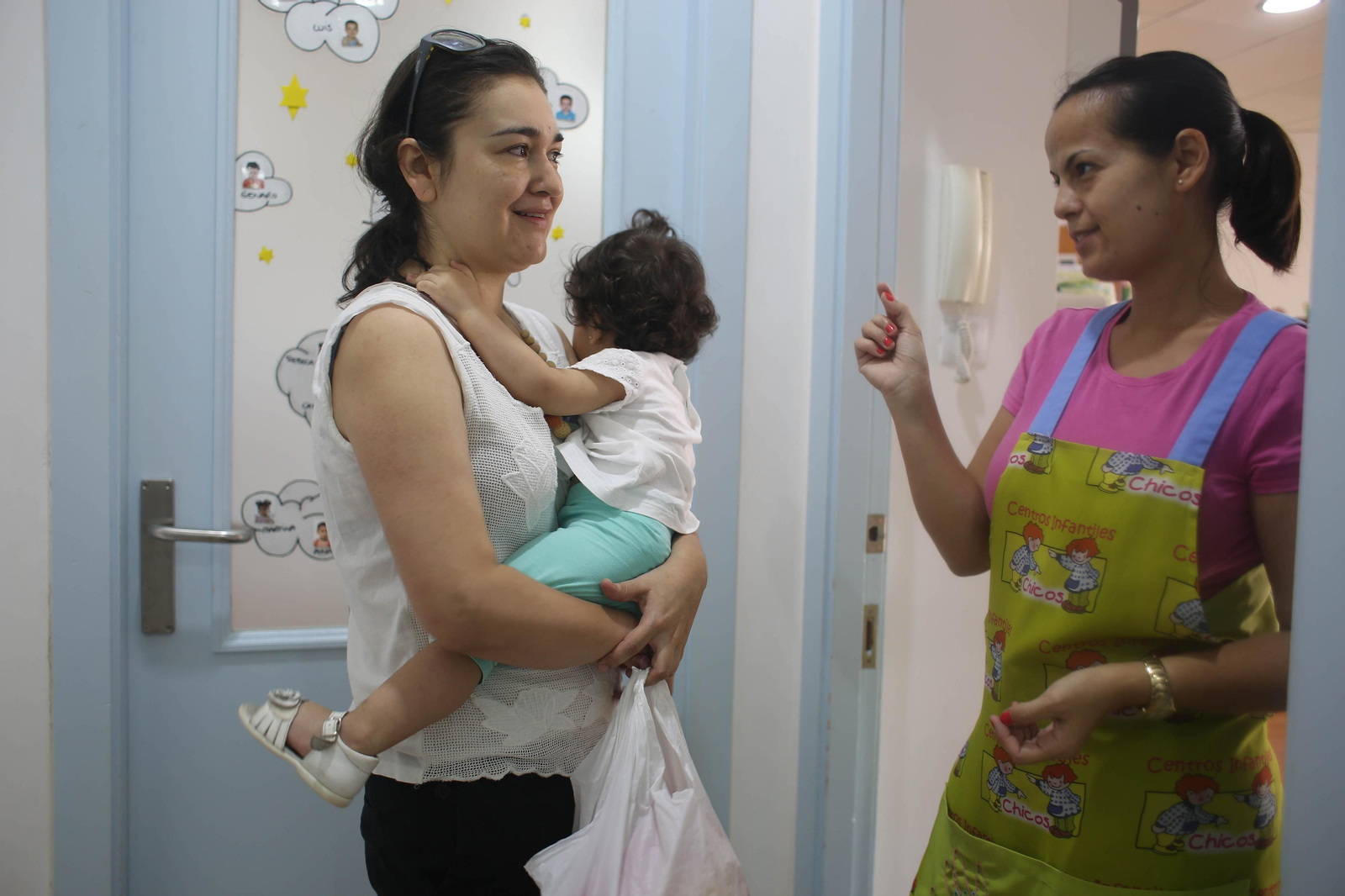 1. Interior de un aula de una escuela infantil, donde los menores atienden a las indicaciones de una profesional. 2. Una madre recoge a su hija en una guardería de la capital. 3. Dos menores junto a su madre, en el momento de la llegada a un centro.