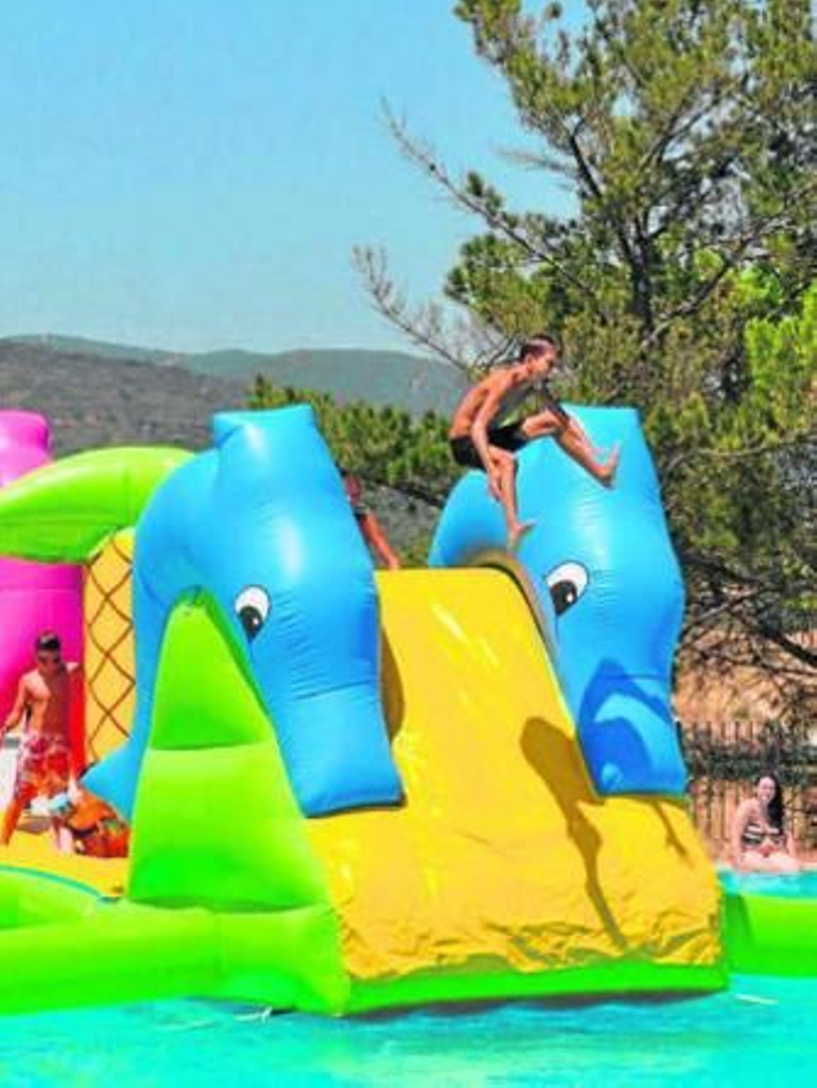 Un joven se lanza al agua desde un castillo hinchable.