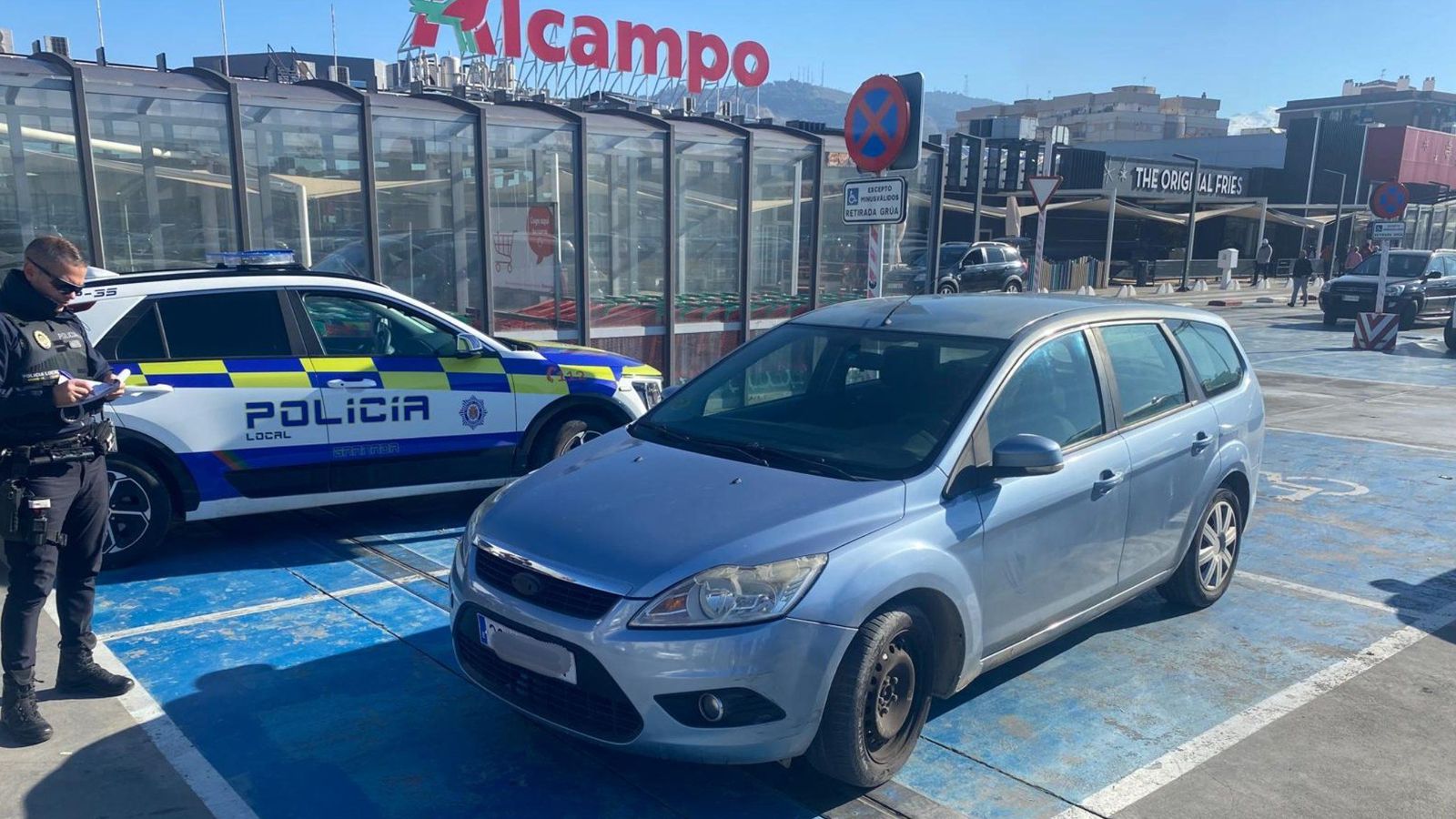 Un agente de la Policía Local de Granada redacta una multa para un vehículo mal aparcado en el parking de un centro comercial
