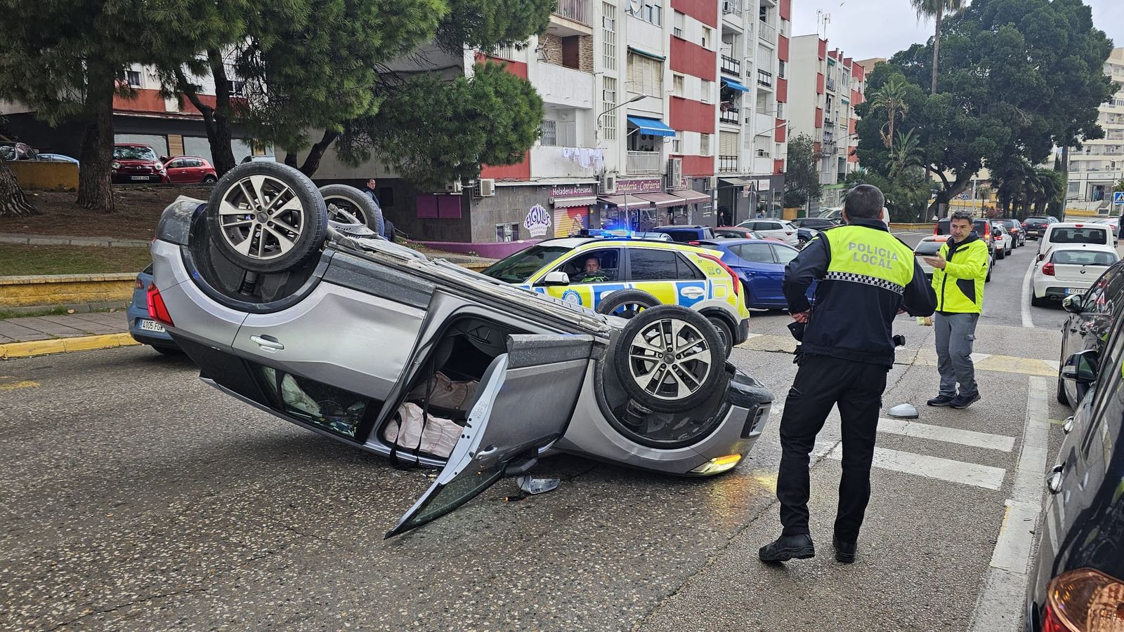 Coche volcado en mitad de la calzada de la calle Pulsera de Algeciras.