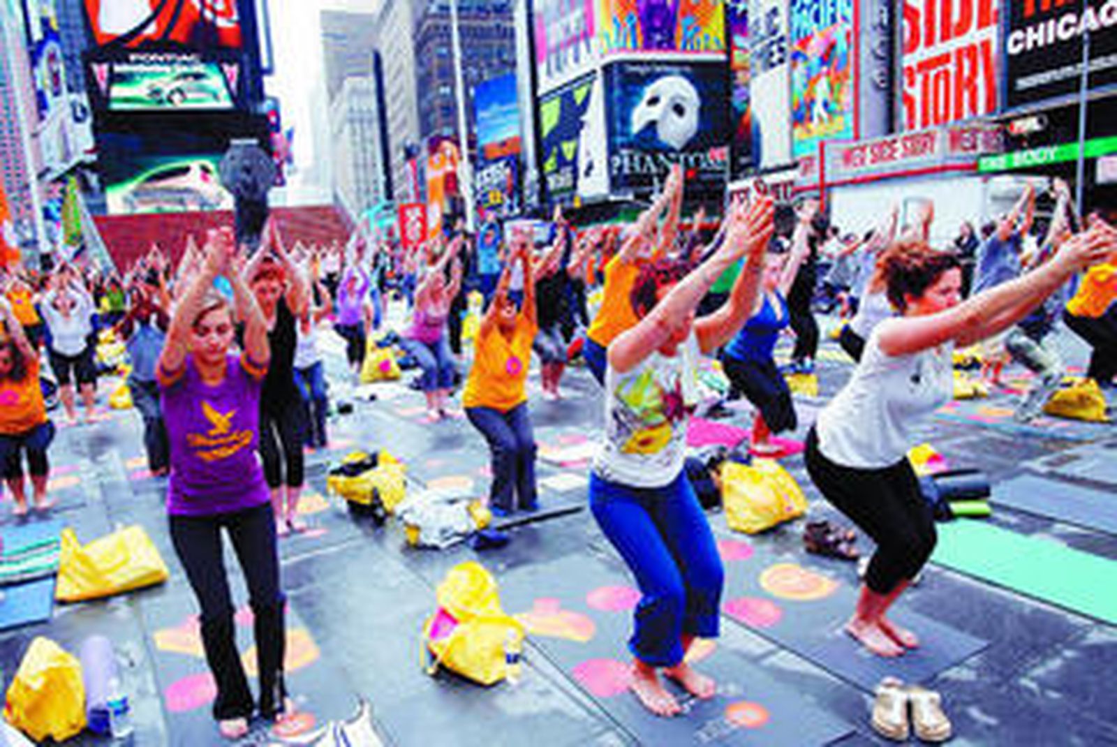 Cerca de 200 personas practican yoga en Times Square, Nueva York, en un acto público.