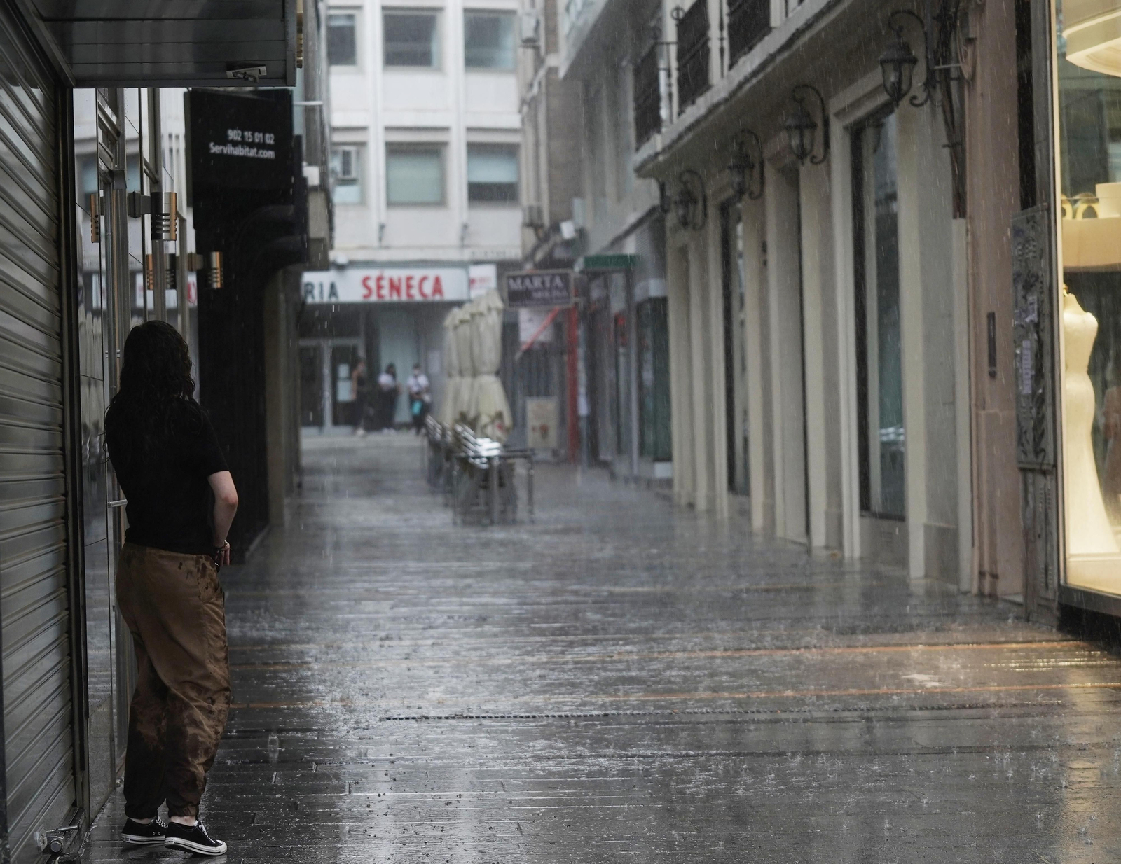Una mujer se cobija de la lluvia en una calle del centro.