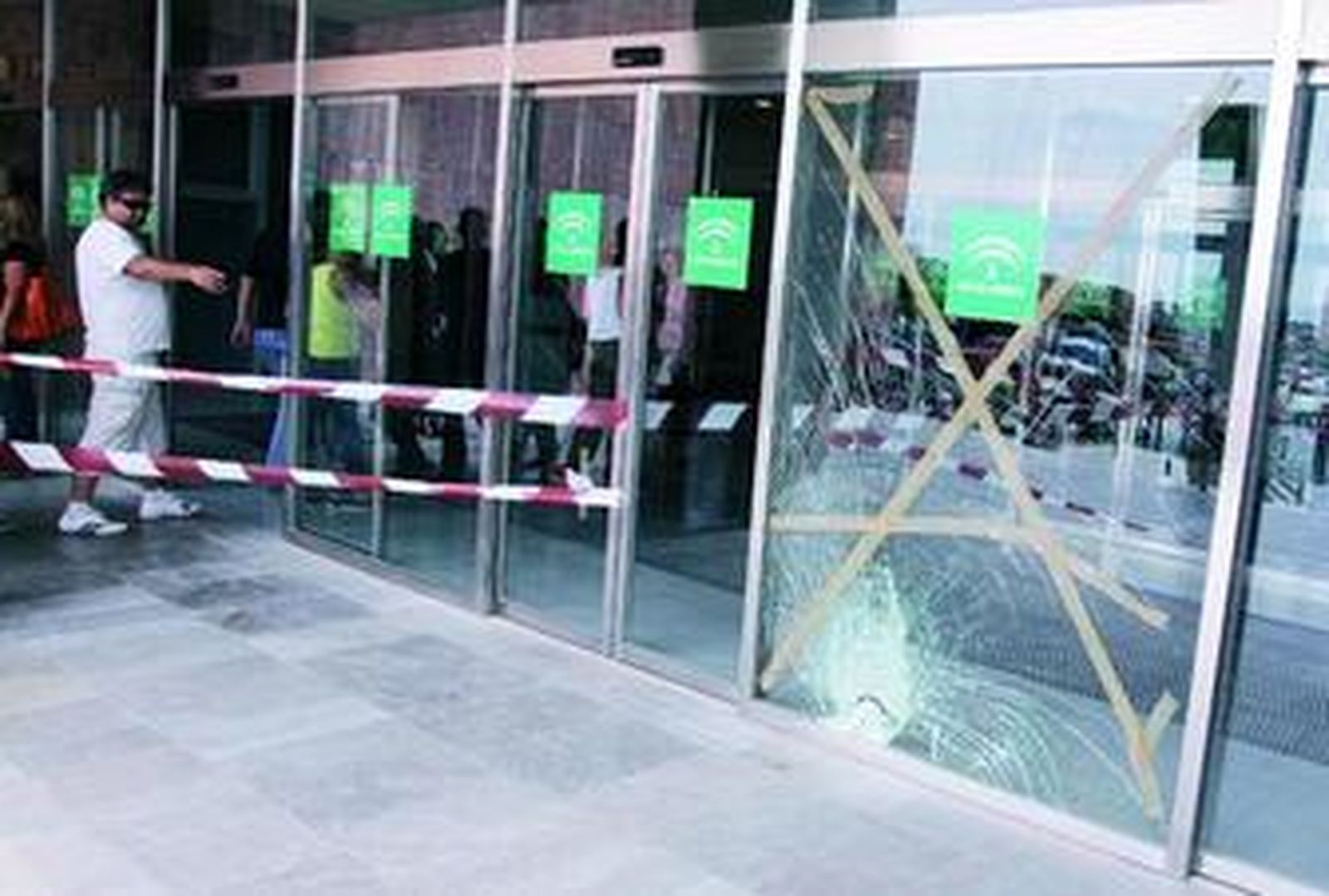 La puerta de cristal de acceso a la Ciudad de la Justicia acordonada tras estrellarse el motorista.