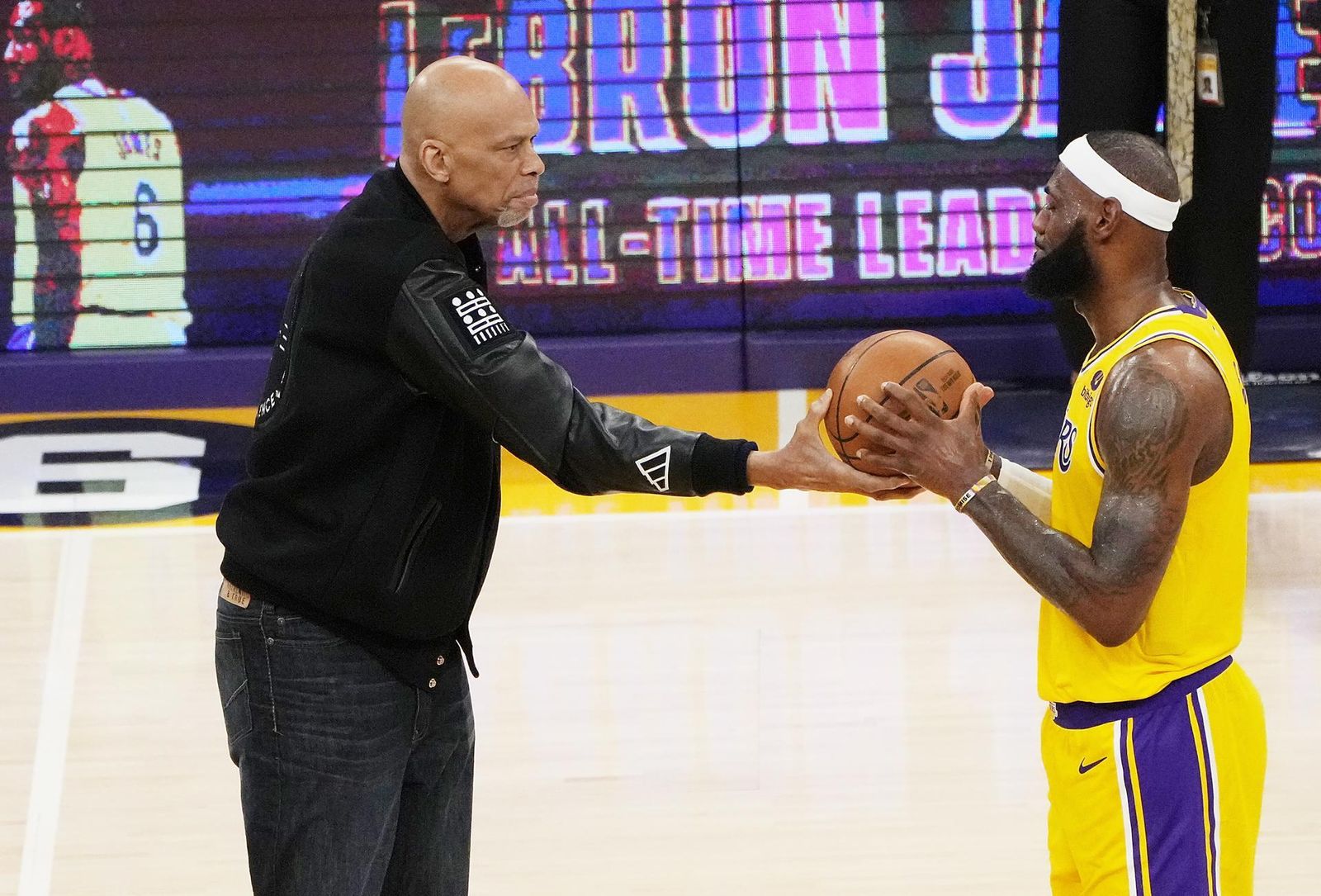 Kareem Abdul-Jabbar le pasa el balón a LeBron James tras batir su marca de anotación.