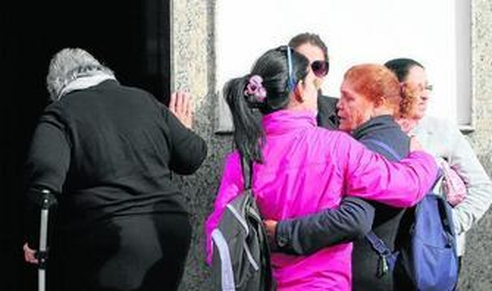 Familiares y vecinos se abrazan en la puerta de la casa de los padres de la víctima.