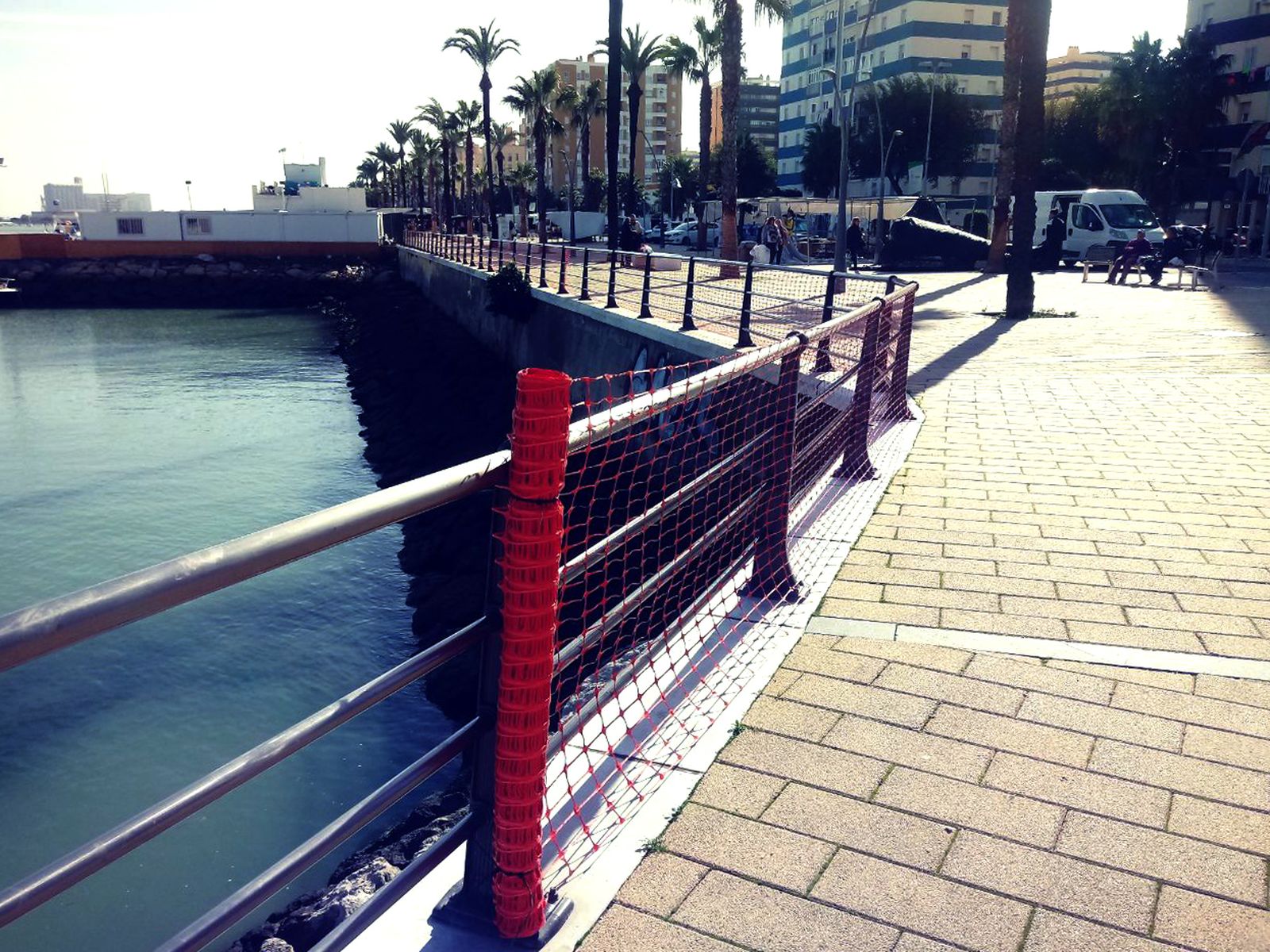Una malla cubre la barandilla del paseo marítimo de la avenida de la Bahía.