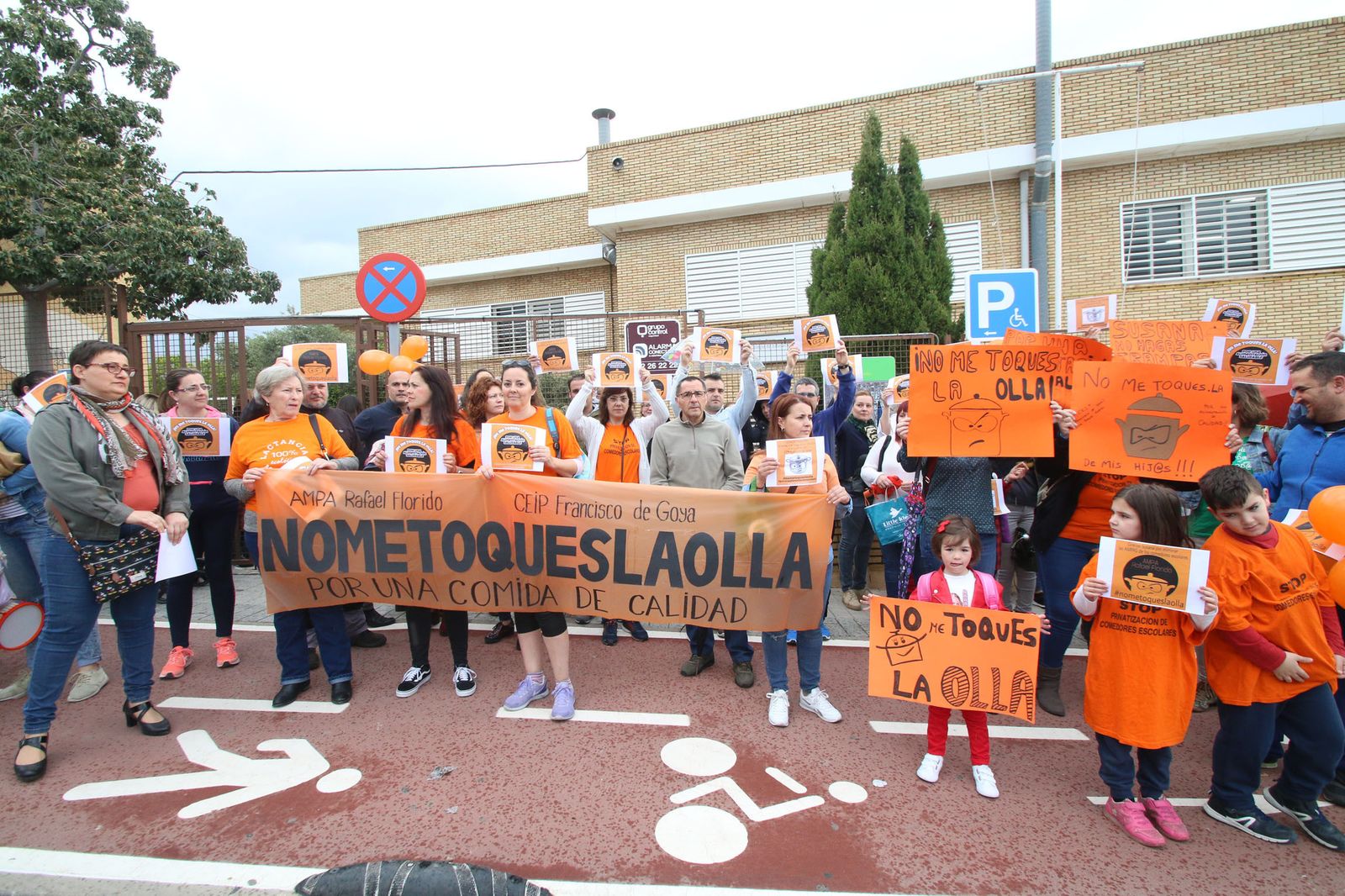 Madres y padres sostienen pancartas en las que reivindican mantener la cocina gestionada por las AMPAS.