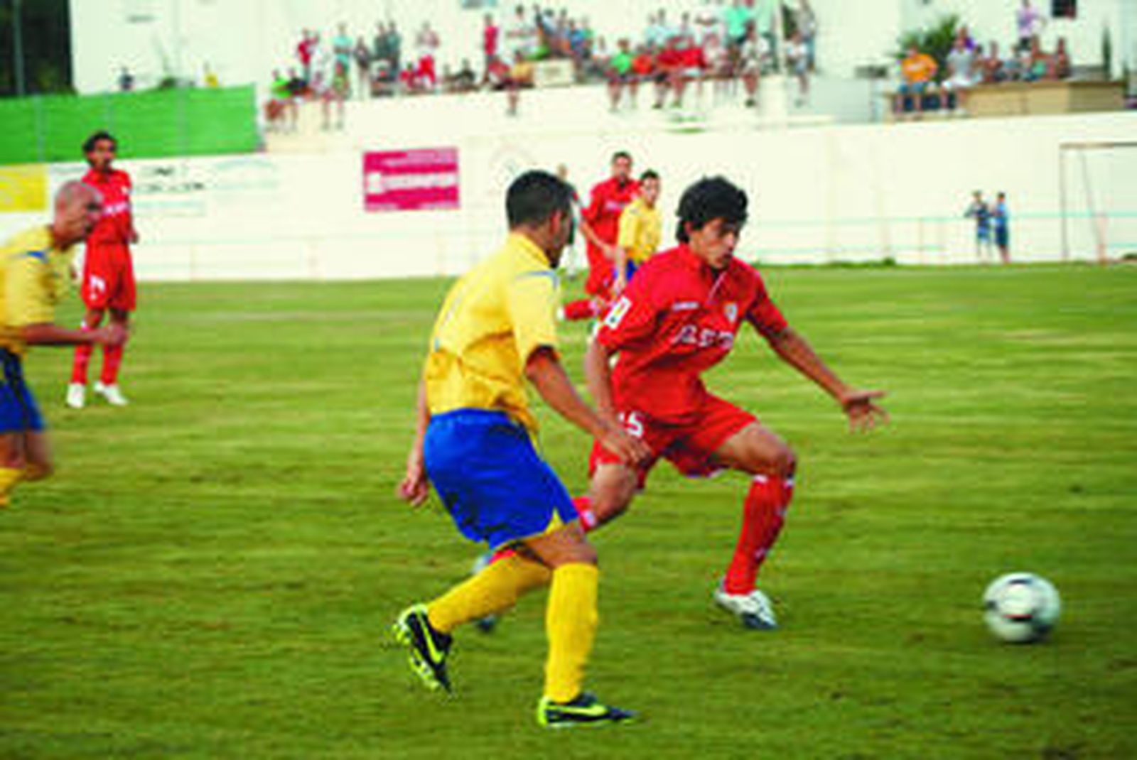 El sevillista Perotti avanza con la pelota junto a un conileño.