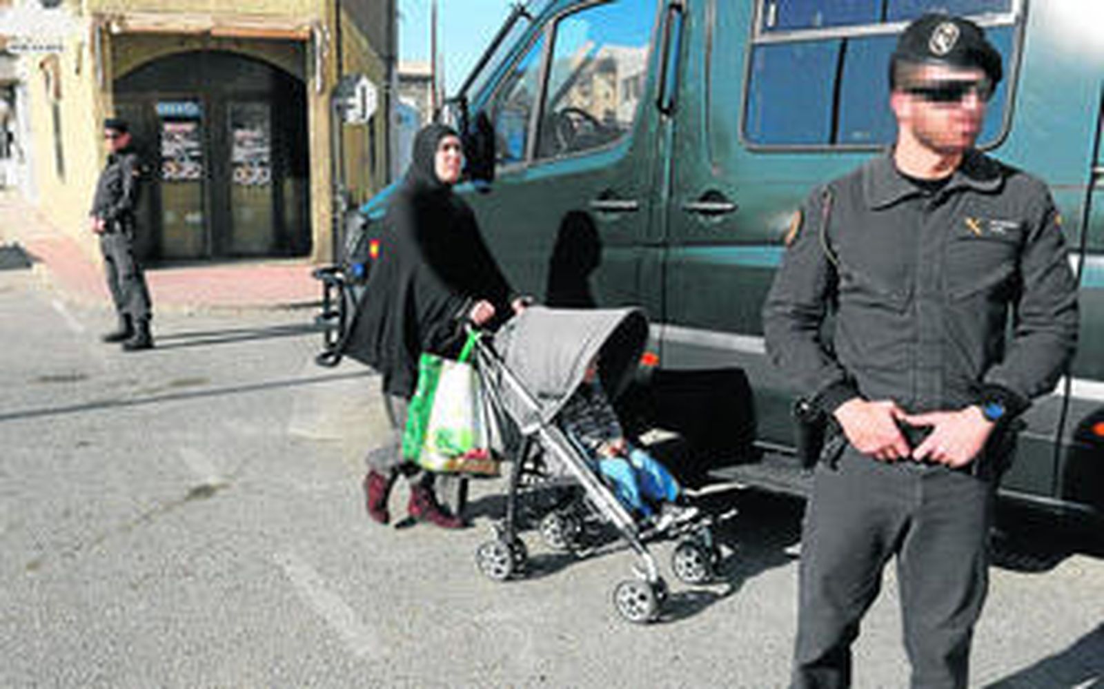 Una mujer musulmana pasa entre dos agentes de la Guardia Civil, en Roquetas de Mar.