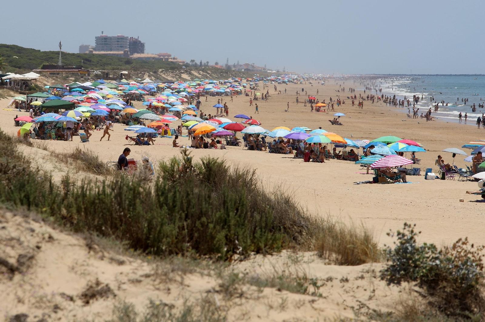 Playa atestada de personas disfrutando del sol y el baño en el mar