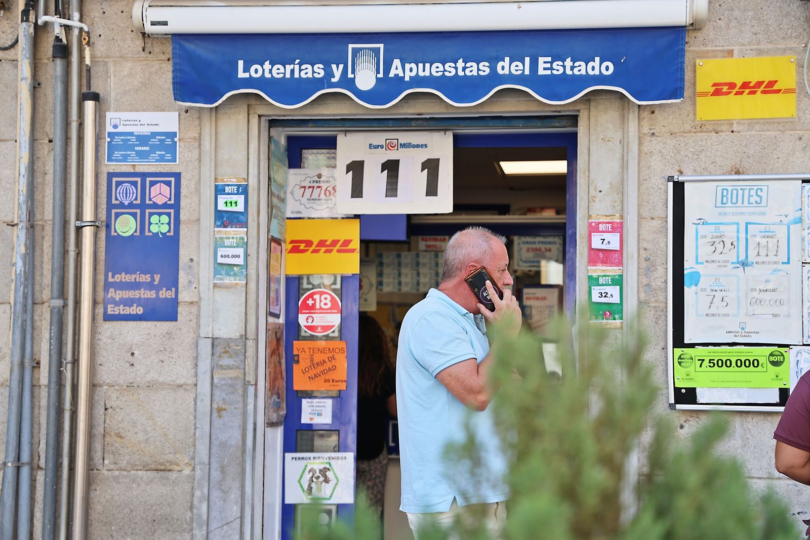 Una persona pasa de largo por delante de una adminsitración de Loterías de Huelva.