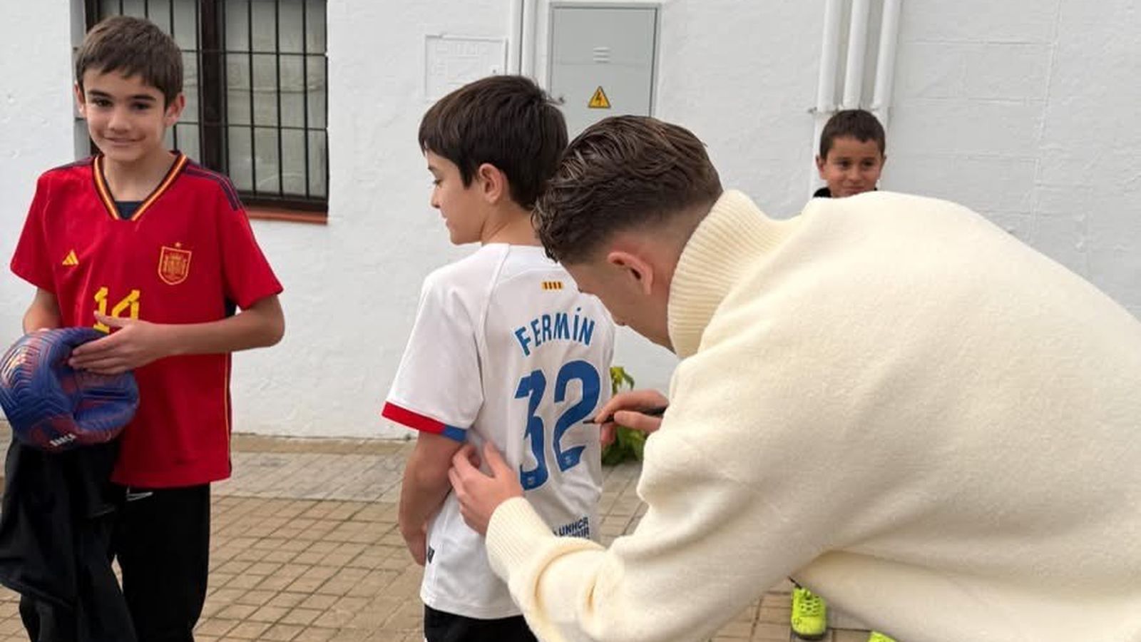 Fermín firma la camiseta a un pequeño vecino de Higuera de la Sierra.