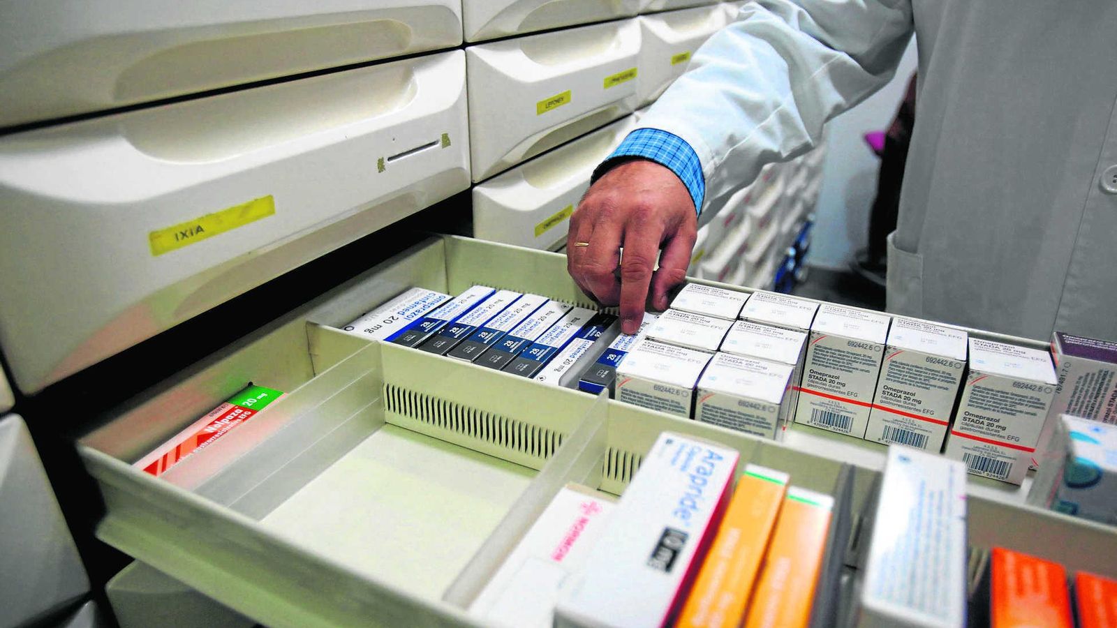 Un farmacéutico busca medicamentos en su farmacia.