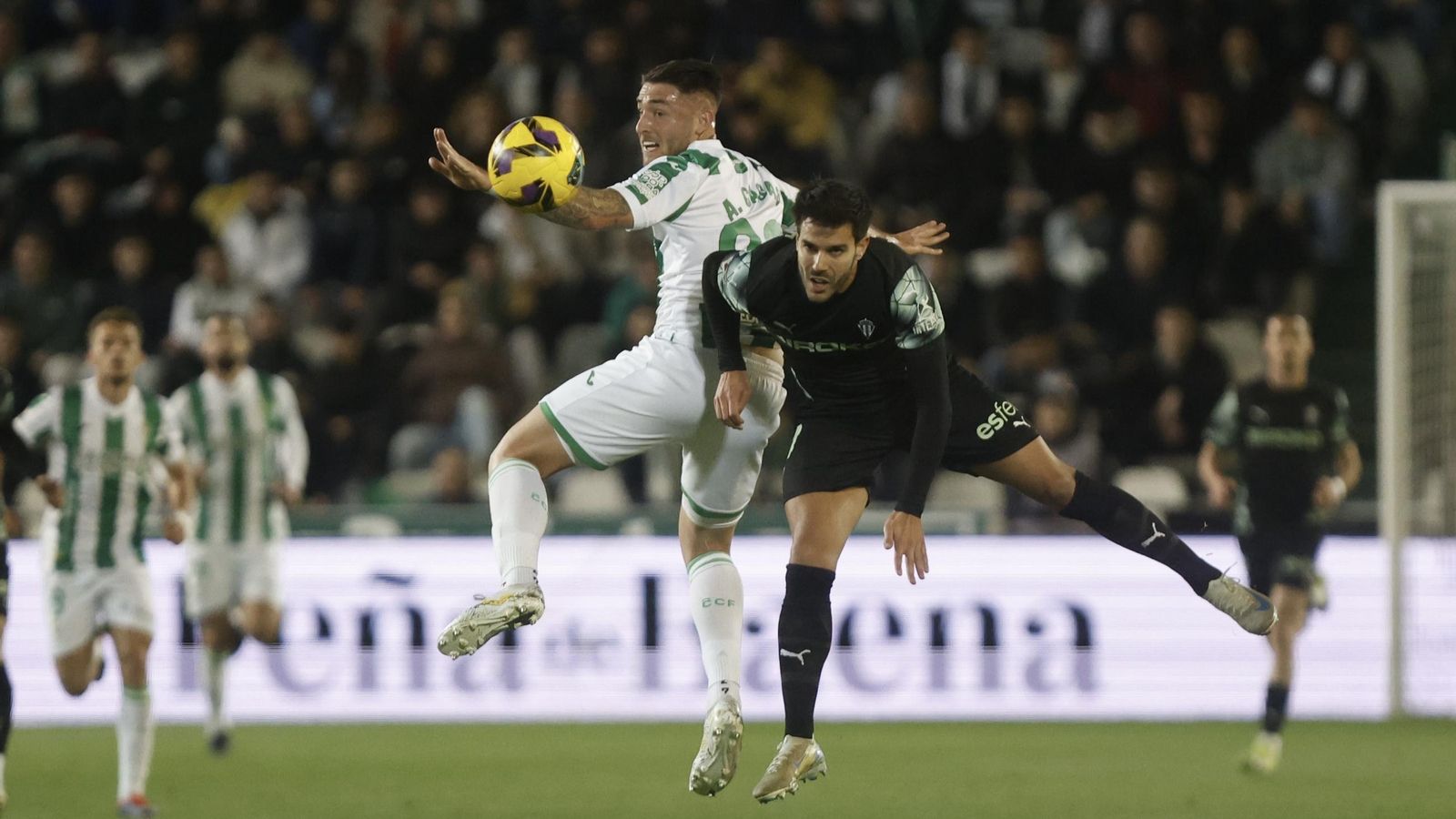 Antonio Casas intenta ganar un balón por alto en el Córdoba CF - Sporting de Gijón.