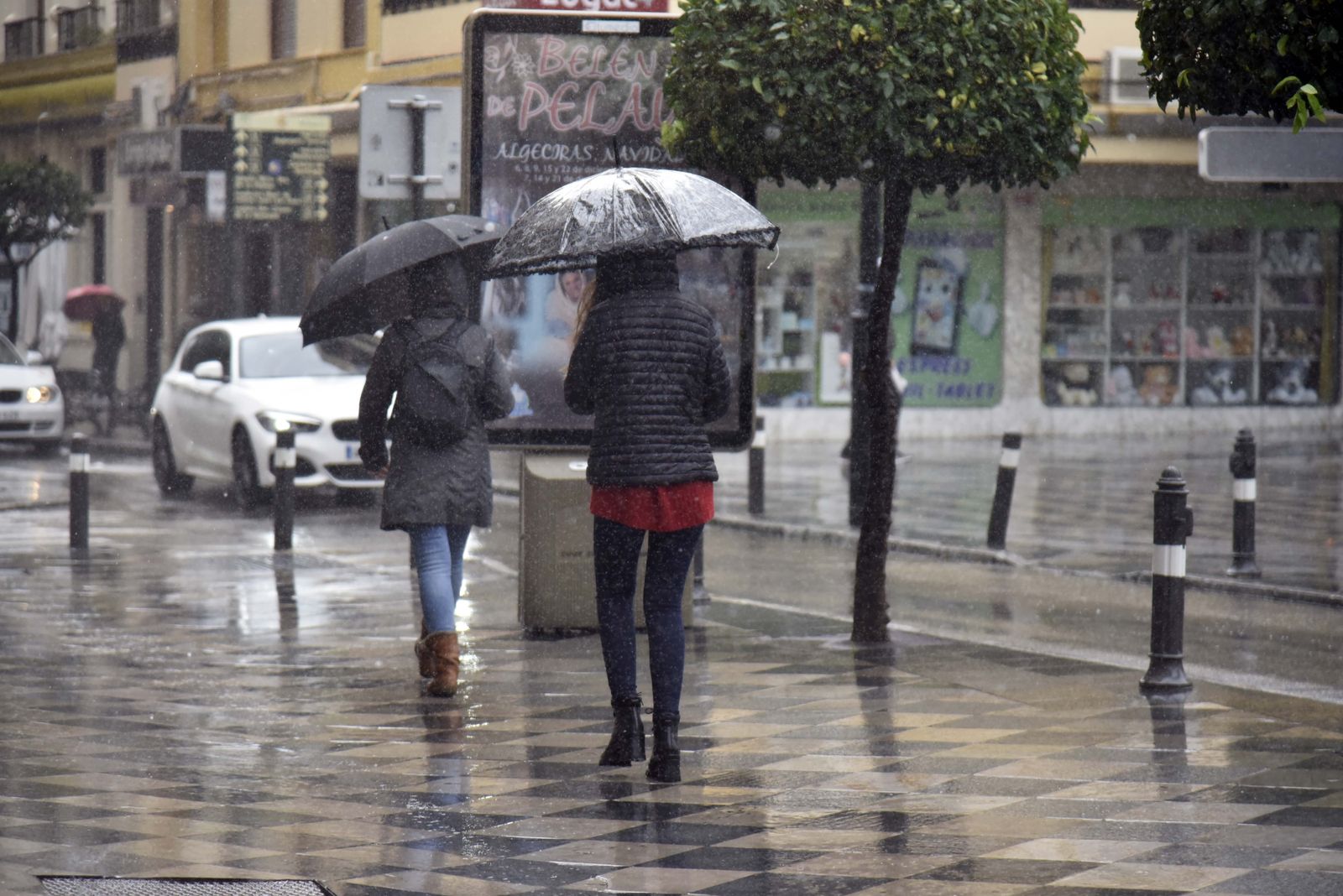 Dos personas, con paraguas junto a la Plaza Alta de Algeciras.