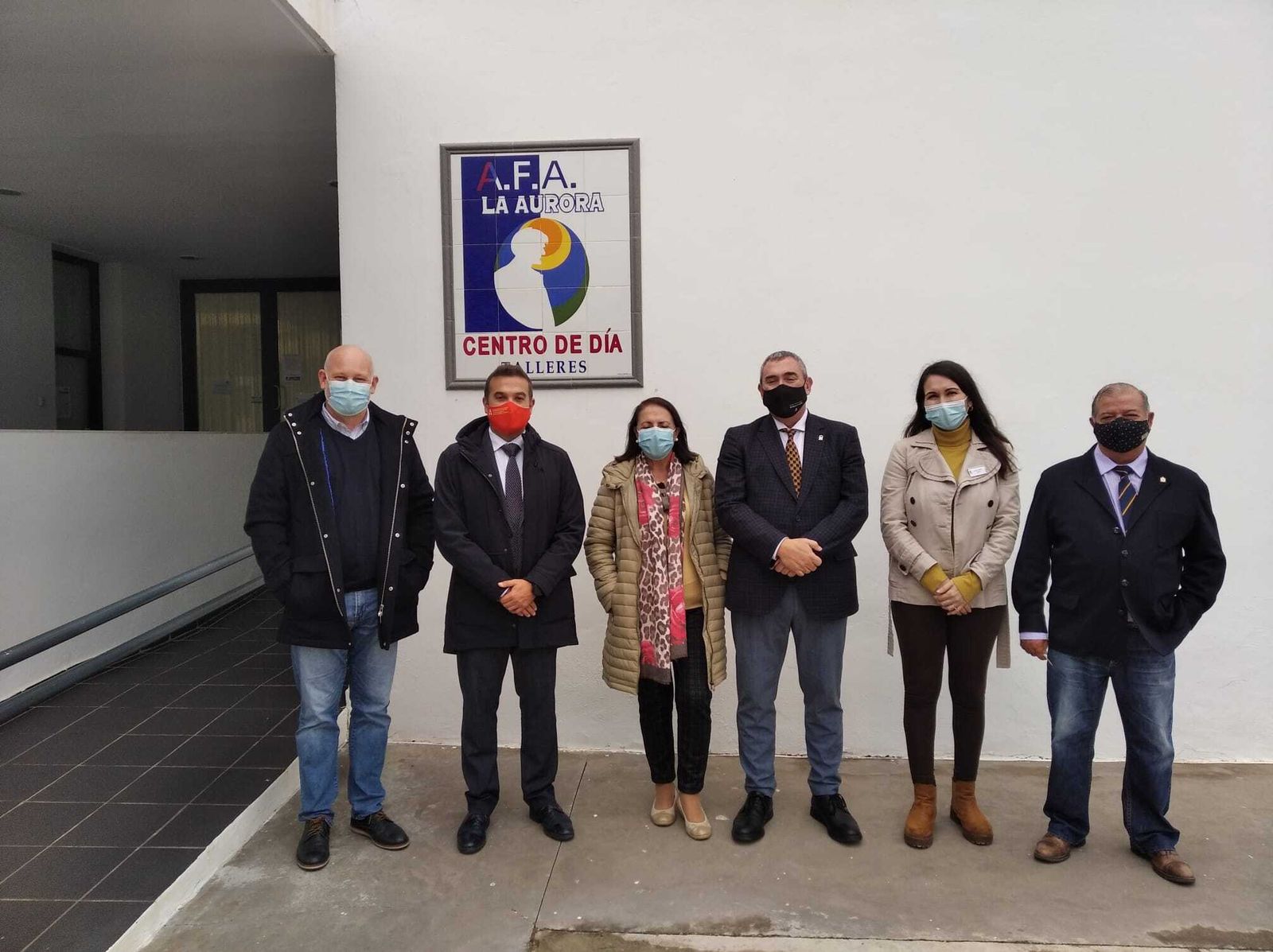Foto  de grupo frente en la entrada de las instalaciones 'La Aurora', situadas en Los Gallos.