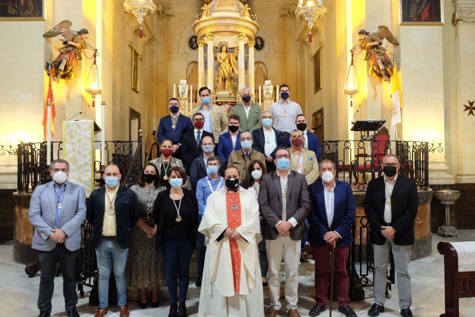 Los responsables del Consejo y de las cofradías locales posan a los pies del altar mayor de la Iglesia de San Juan Bautista junto al arcipreste de la ciudad.