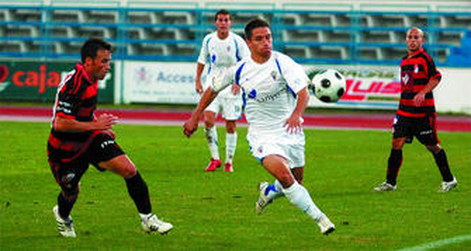 Un jugador marbellí trata de llevarse el balón ante la presión de un rival.