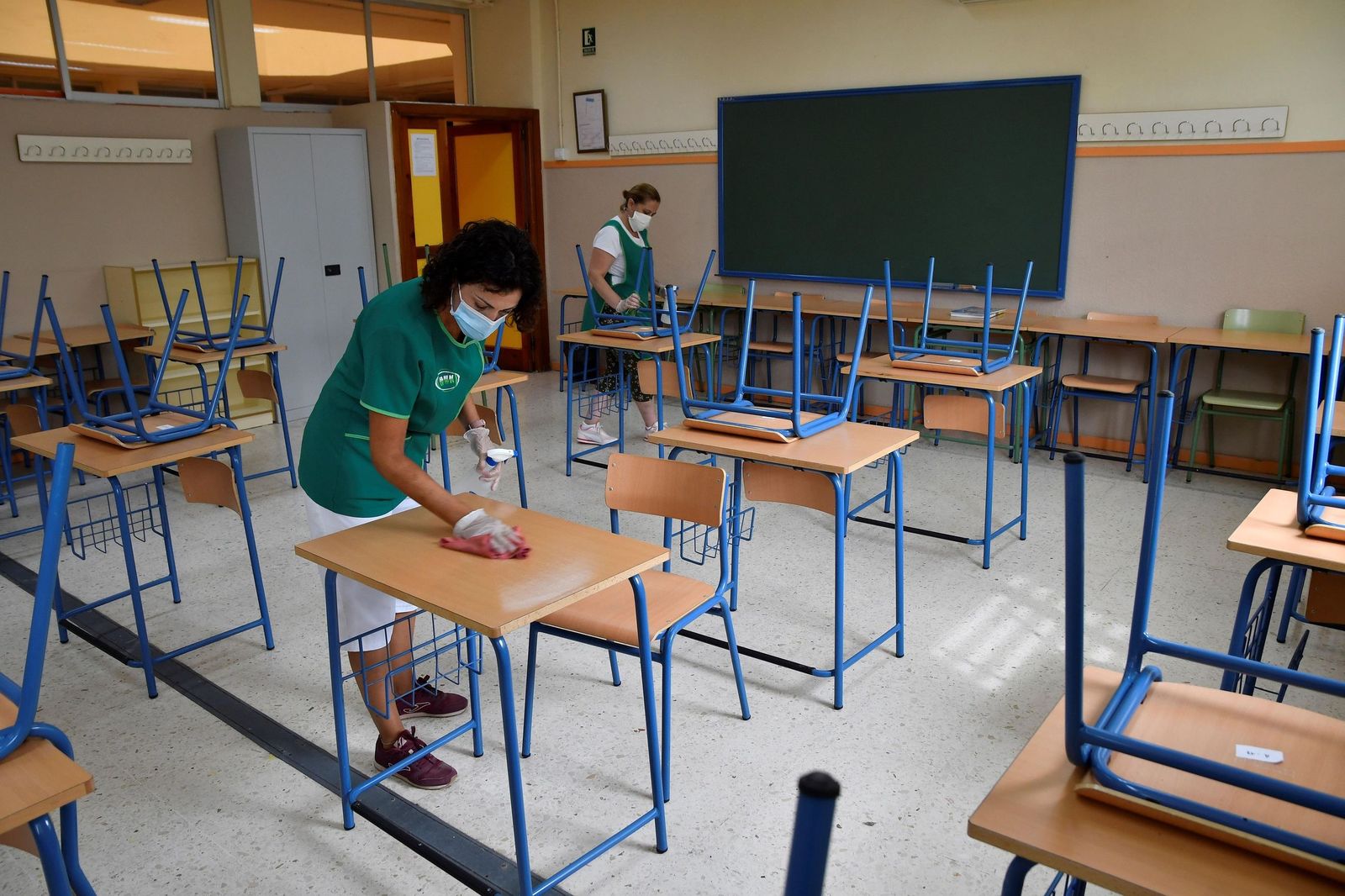 Dos trabajadoras limpiando el aula de un colegio.