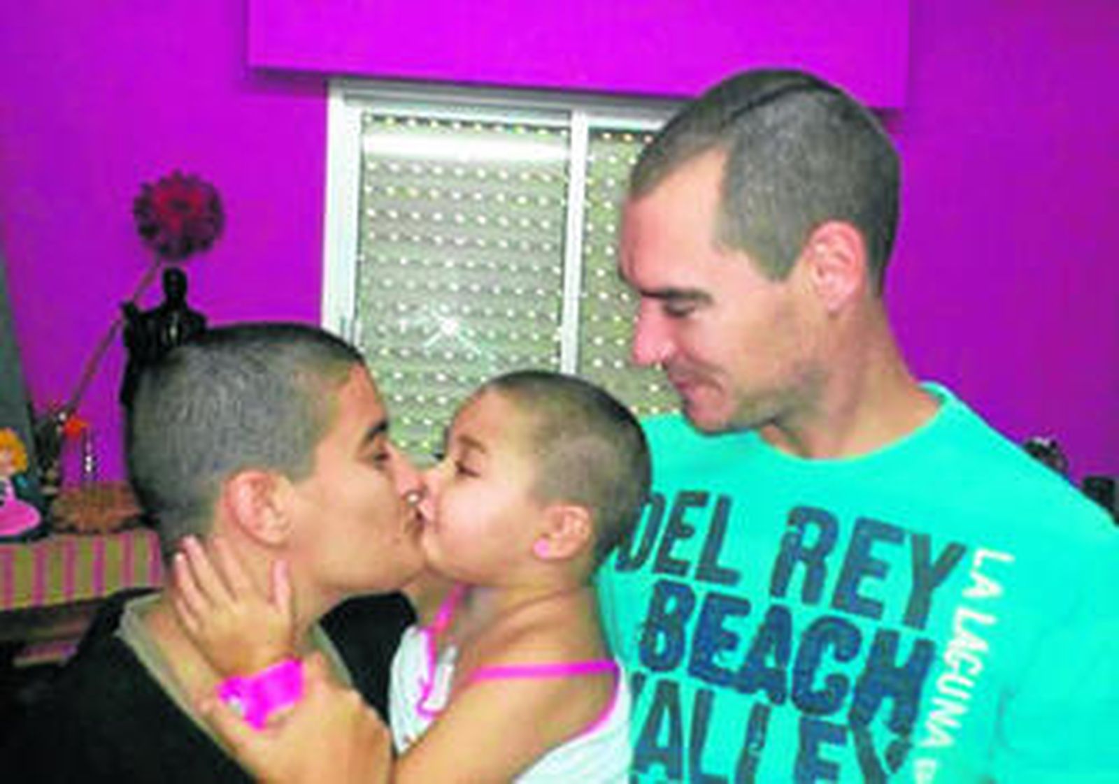 La pequeña junto a sus padres, todos con el pelo corto.