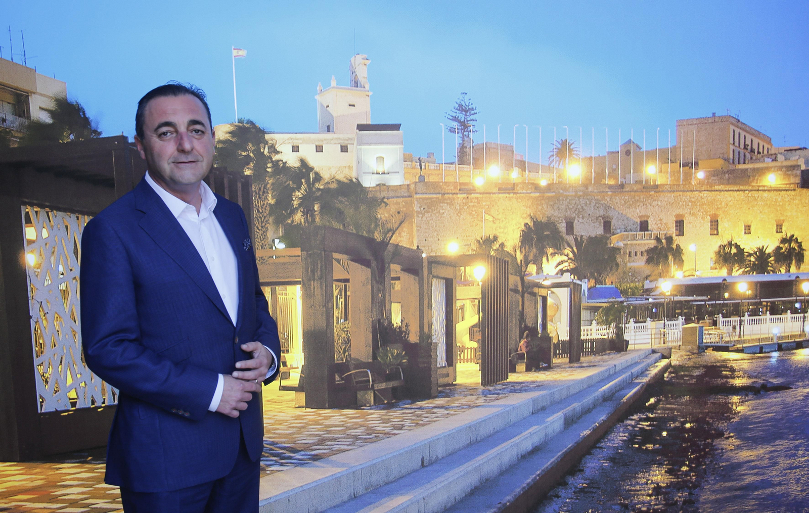 El viceconsejero de Turismo de Melilla posa frente a un cartel del puerto de la ciudad autónoma.